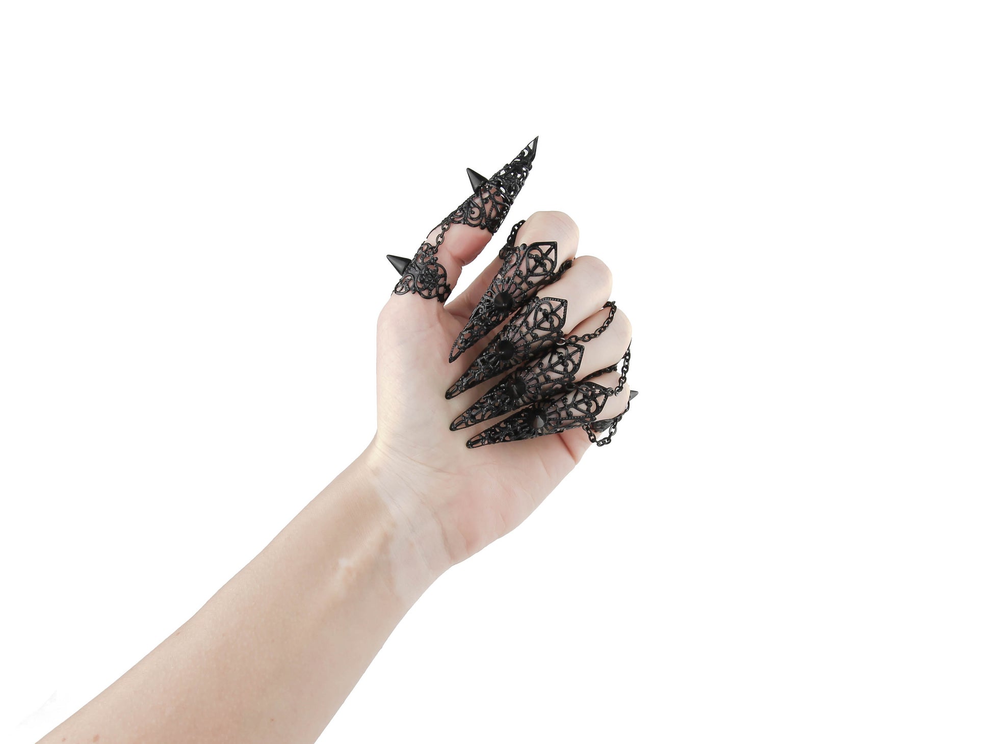 A set of black claw rings with studs adorns a hand, exemplifying the dark-avantgarde style of Myril Jewels. These bold, neo-gothic pieces are a fit for Halloween, adding a punk edge to gothic-chic looks, perfect for the fashion-forward goth girlfriend or as a daring festival jewel.