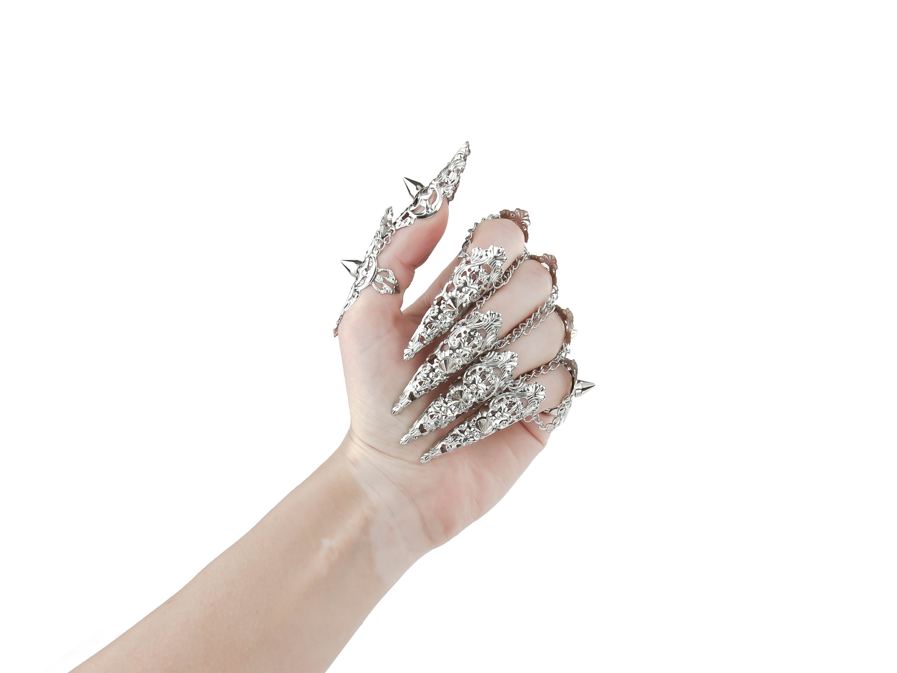  A hand is fully adorned with Myril Jewels' studded nail claw rings, each featuring a detailed silver design with sharp, edgy protrusions. These rings showcase a bold neo-goth aesthetic, perfect for dark-avantgarde fashion enthusiasts. The set is an ideal choice for creating a dramatic look at Halloween events, embodying the gothic-chic and whimsigoth spirit, and is also suited for witchcore, everyday wear, or as statement jewelry for rave parties and festivals.