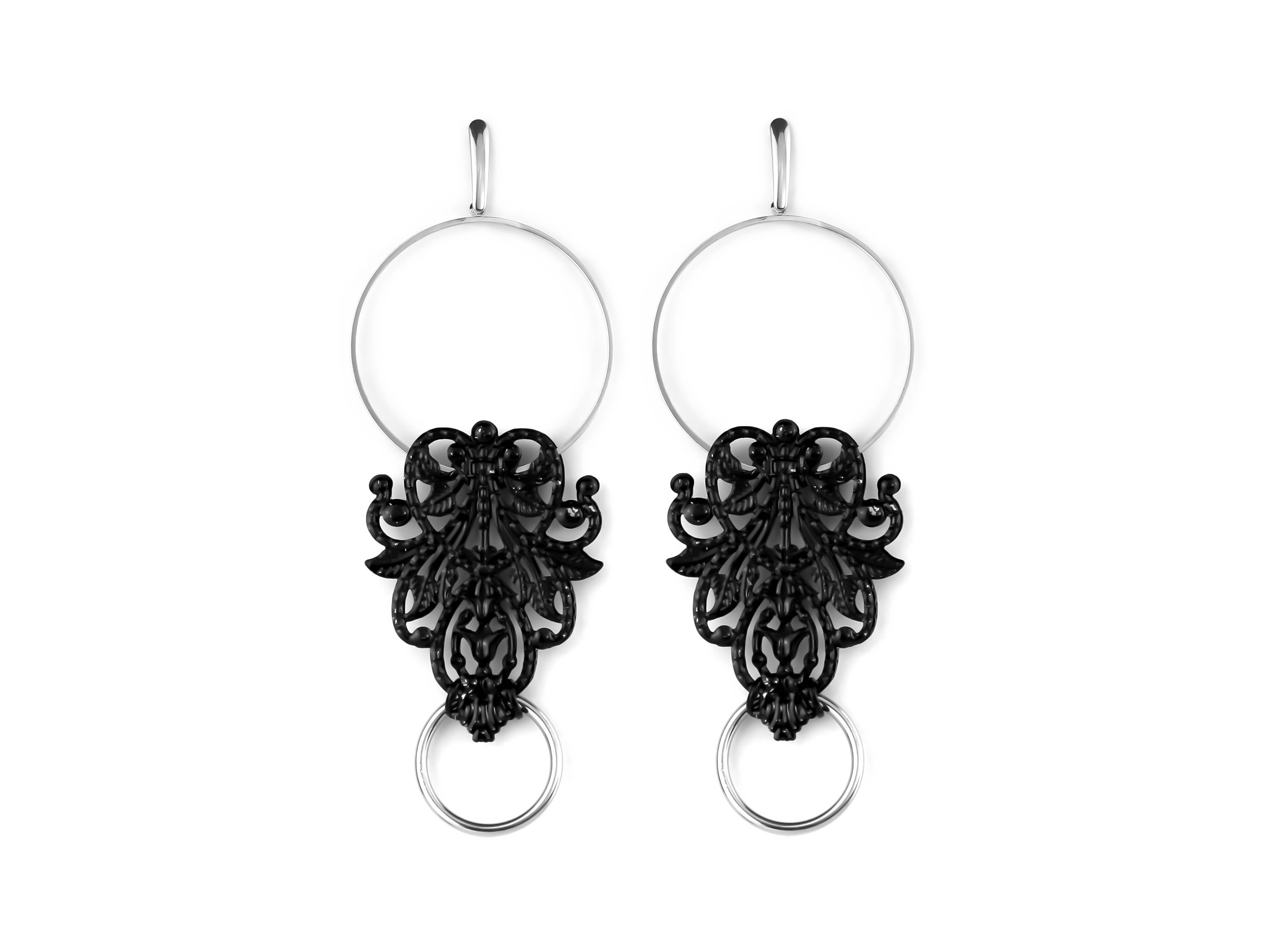 This image features a pair of black and silver filigree hoop earrings from Myril Jewels, perfect for those with a taste for dark, avant-garde accessories. The intricate filigree design on the earrings exudes gothic charm, making them suitable for a Halloween ensemble, everyday goth wear, or as an eye-catching addition to a festival outfit. They serve as a bold statement piece for anyone embracing a neo-gothic, witchcore, or whimsigoth aesthetic.