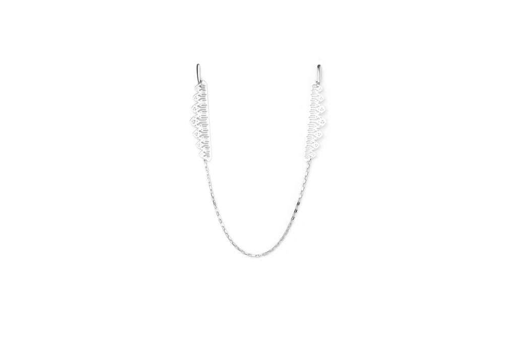 Innovative Myril Jewels one-piece earring, crafted in a striking silver tone for a neo-gothic impression. This unique accessory, linking one ear to the other with a delicate chain, is designed for the edgy minimalist goth. It's a versatile piece that complements both everyday and rave party attire, making it a perfect goth girlfriend or friend gift idea for those who favor gothic-chic and witchcore aesthetics