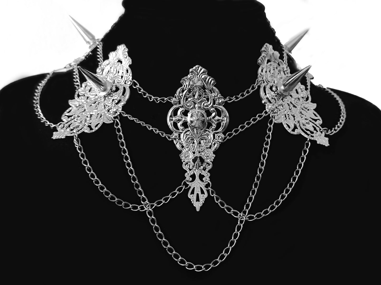 An elaborate Myril Jewels studded choker featuring intricate filigree work with sharp spikes, connected by multiple fine chains that create a lavish draped effect. This bold, gothic-chic necklace epitomizes dark-avantgarde style, ideal for enhancing festival, drag, or everyday witchcore attire.
