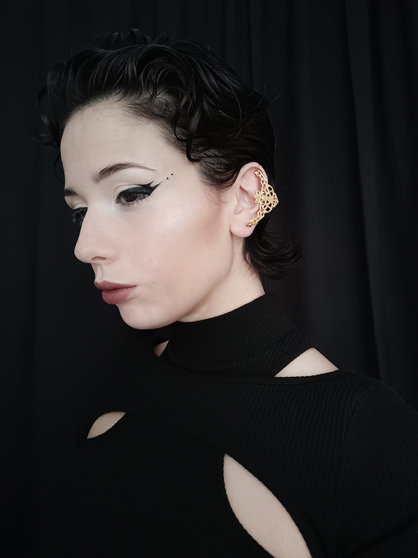 A profile view of a model wearing Myril Jewels' intricate gold cuff earrings, showcasing a neo-gothic design that complements the gothic and alternative style. The gold earrings feature an ornate filigree pattern that covers the ear with a touch of gothic-chic elegance, perfect for everyday wear or as a distinctive accent for festival jewels. Their elaborate craftsmanship captures the essence of Halloween jewelry, aligning with the whimsigoth and witchcore aesthetics