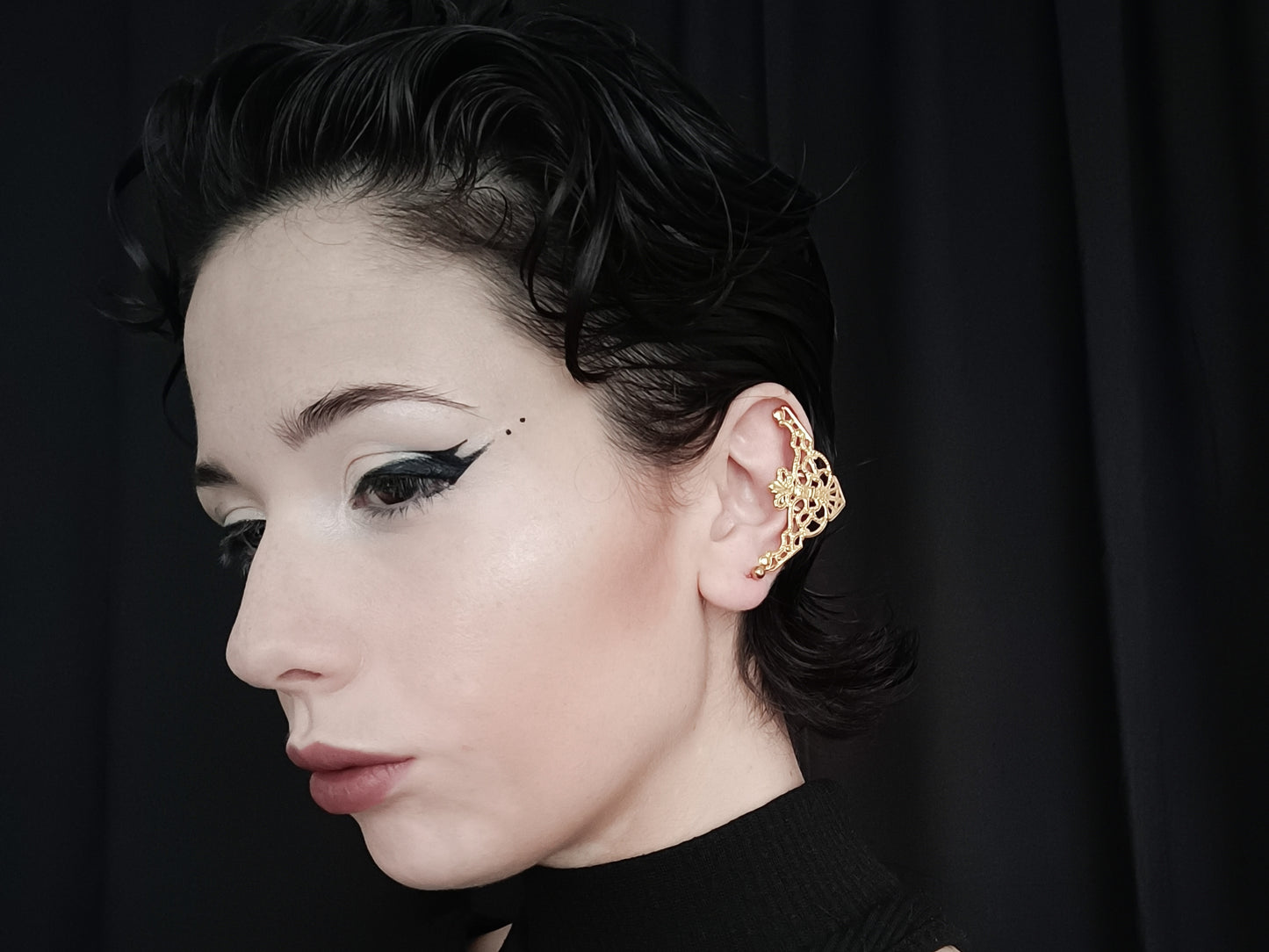 A profile view of a model wearing Myril Jewels' intricate gold cuff earrings, showcasing a neo-gothic design that complements the gothic and alternative style. The gold earrings feature an ornate filigree pattern that covers the ear with a touch of gothic-chic elegance, perfect for everyday wear or as a distinctive accent for festival jewels. Their elaborate craftsmanship captures the essence of Halloween jewelry, aligning with the whimsigoth and witchcore aesthetics