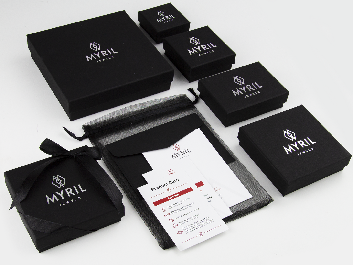  A refined collection of Myril Jewels packaging showcases elegant, black, variably-sized boxes adorned with the company's silver logo, complemented by detailed care instructions and sophisticated black organza gift bags. This ensemble epitomizes the brand's commitment to a refined goth aesthetic, offering a glimpse into the avant-garde elegance and meticulous attention to detail that define Myril Jewels' identity.