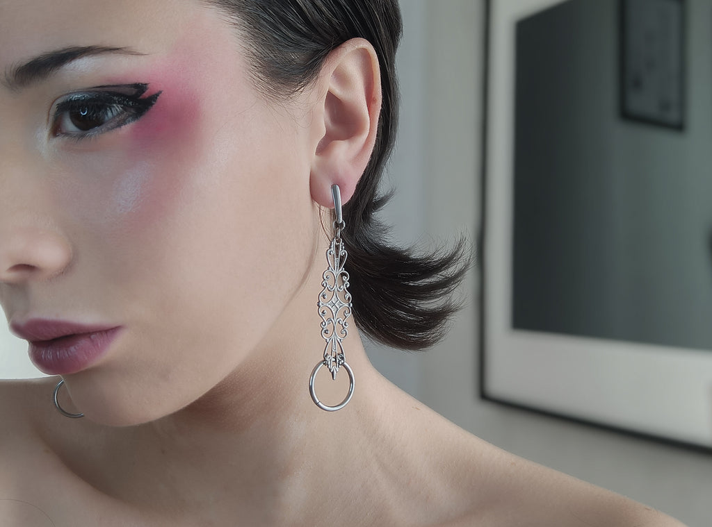 A close-up view of a woman wearing Myril Jewels' filigree-shaped earrings with an O-ring accent, embodying neo-gothic style perfect for alternative fashion lovers