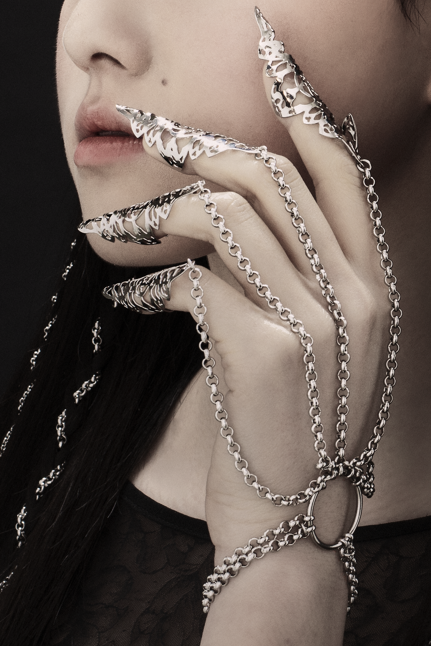 A dramatic hand chain bracelet with nail claws from Myril Jewels enhances the beauty of a gothic look. With its neo-gothic flair, this jewelry piece is a striking choice for Halloween, goth-inspired everyday wear, or as a bold accent for festival outfits and drag queen glamor.