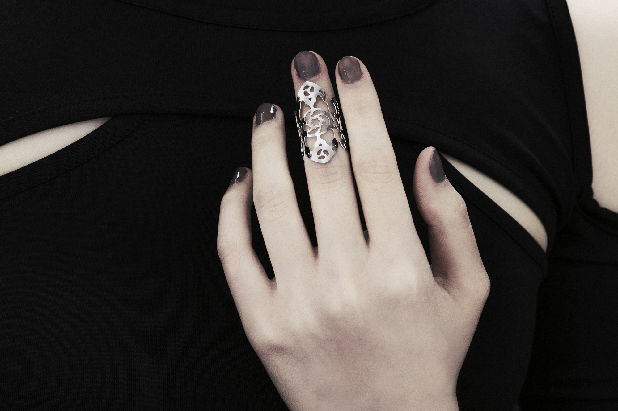 A hand adorned with a Myril Jewels gothic architecture inspired midi ring, set against a black sleeveless top with cut-out details. The ring’s intricate silver filigree design is reminiscent of the ornate complexity of gothic cathedrals, perfect for those who appreciate the dark-avantgarde, neo-goth aesthetic. This piece is a staple for gothic-chic fashion, a subtle nod to whimsigoth and witchcore styles, and an ideal accessory for Halloween, everyday wea