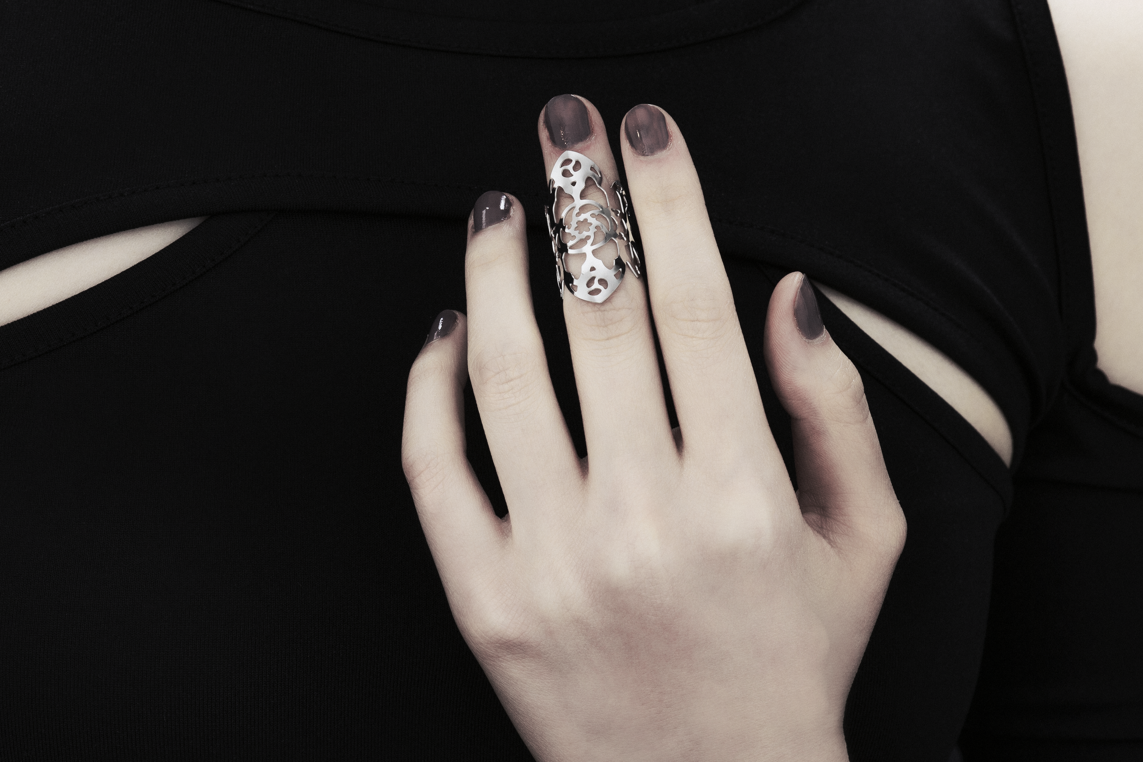 A hand adorned with a Myril Jewels gothic architecture inspired midi ring, set against a black sleeveless top with cut-out details. The ring’s intricate silver filigree design is reminiscent of the ornate complexity of gothic cathedrals, perfect for those who appreciate the dark-avantgarde, neo-goth aesthetic. This piece is a staple for gothic-chic fashion, a subtle nod to whimsigoth and witchcore styles, and an ideal accessory for Halloween, everyday wea