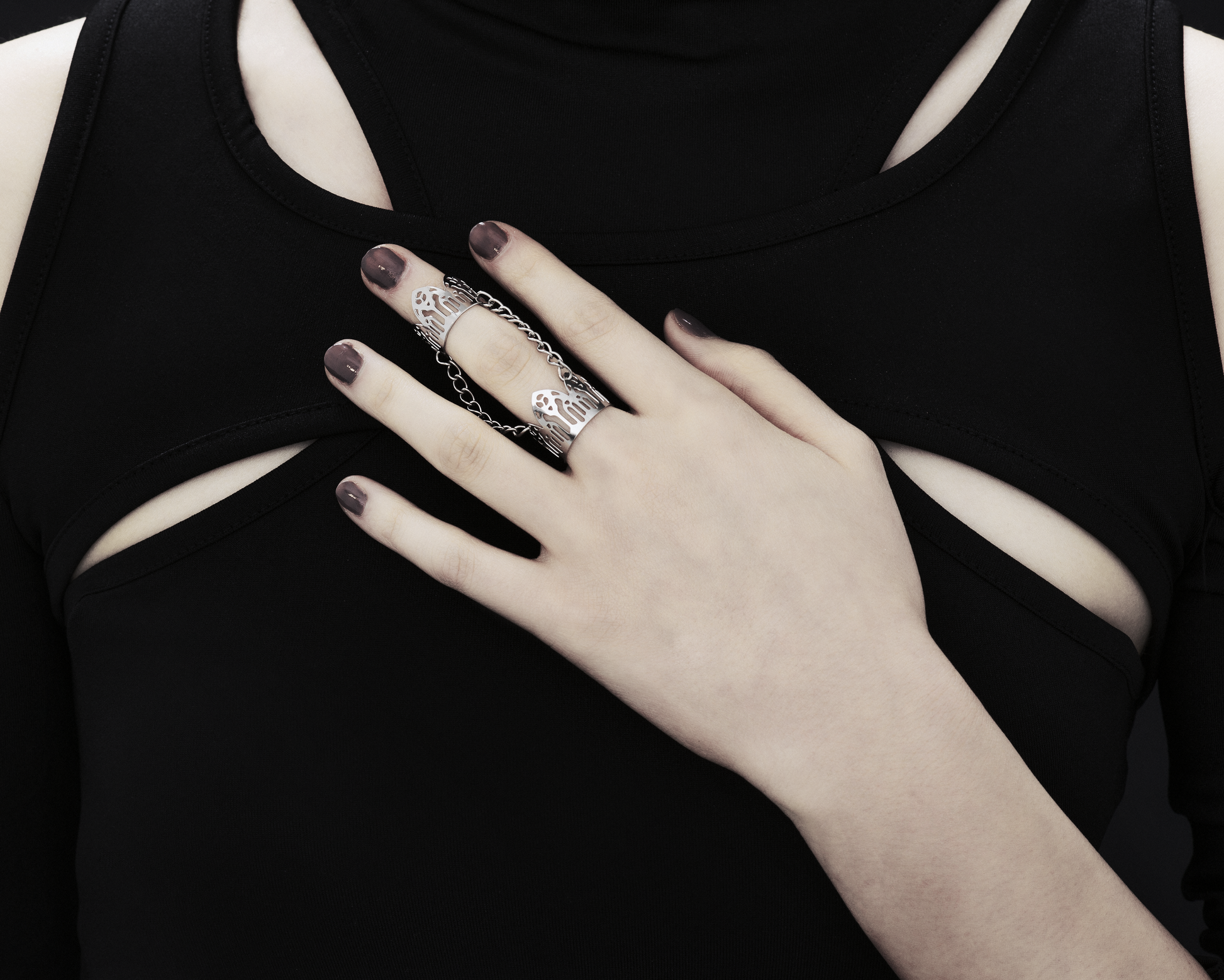 An image featuring a hand adorned with a Myril Jewels gothic arches inspired double ring. The ring, embodying dark-avantgarde and neo-gothic styles, wraps elegantly around two fingers, reflecting the brand's commitment to gothic-chic aesthetics. This unique piece is ideal for those who resonate with Halloween and punk jewelry trends, adding an edge to everyday wear, and complements a whimsigoth or witchcore wardrobe, perfect for rave party or festival occasions.