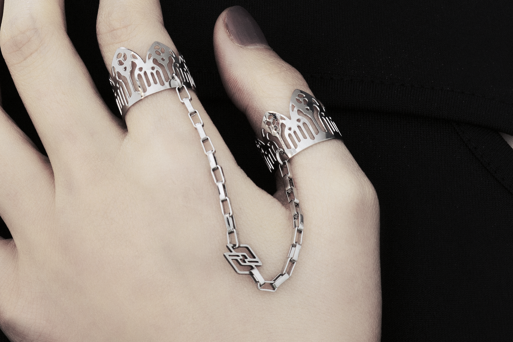 Behold a splendid exhibition of Myril Jewels' hand-wrought, avant-garde double rings, adorned upon a hand. Each ring flaunts elaborate designs inspired by Gothic artistry, catering to aficionados of the gothic and alternative fashion spheres. Crafted with a delicate band that echoes the majestic forms of gothic cathedrals, the rings make a sophisticated statement. These creations, forged in Italy, capture the distinct and dynamic essence of Myril Jewels