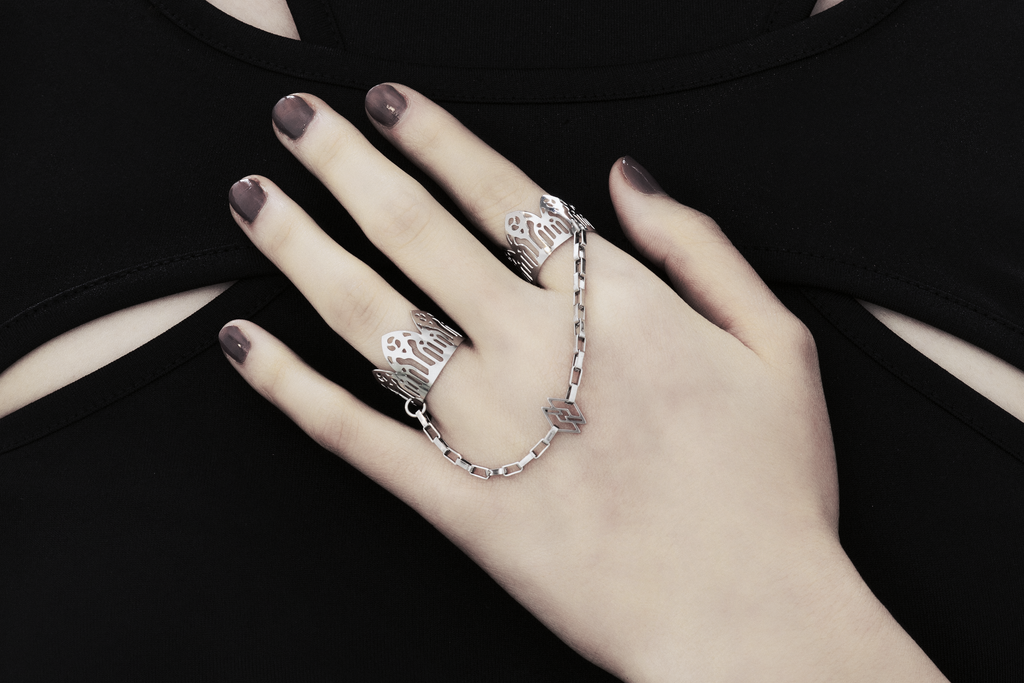Behold a splendid exhibition of Myril Jewels' hand-wrought, avant-garde double rings, adorned upon a hand. Each ring flaunts elaborate designs inspired by Gothic artistry, catering to aficionados of the gothic and alternative fashion spheres. Crafted with a delicate band that echoes the majestic forms of gothic cathedrals, the rings make a sophisticated statement. These creations, forged in Italy, capture the distinct and dynamic essence of Myril Jewels