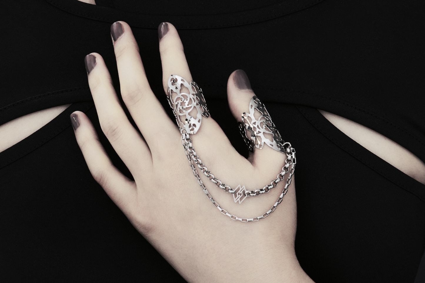 Showcased here is a hand-adorned Myril Jewels double ring, exuding dark sophistication. Crafted with minute gothic details, this piece is perfect for aficionados of the goth and alternative scene. With a design reminiscent of gothic architecture, the slender band proclaims a subtle yet bold elegance. Made in Italy, these rings are a testament to Myril Jewels' distinct and evolving dark avant-garde aesthetic, specifically catered to the refined palate of gothic jewelry admirers.