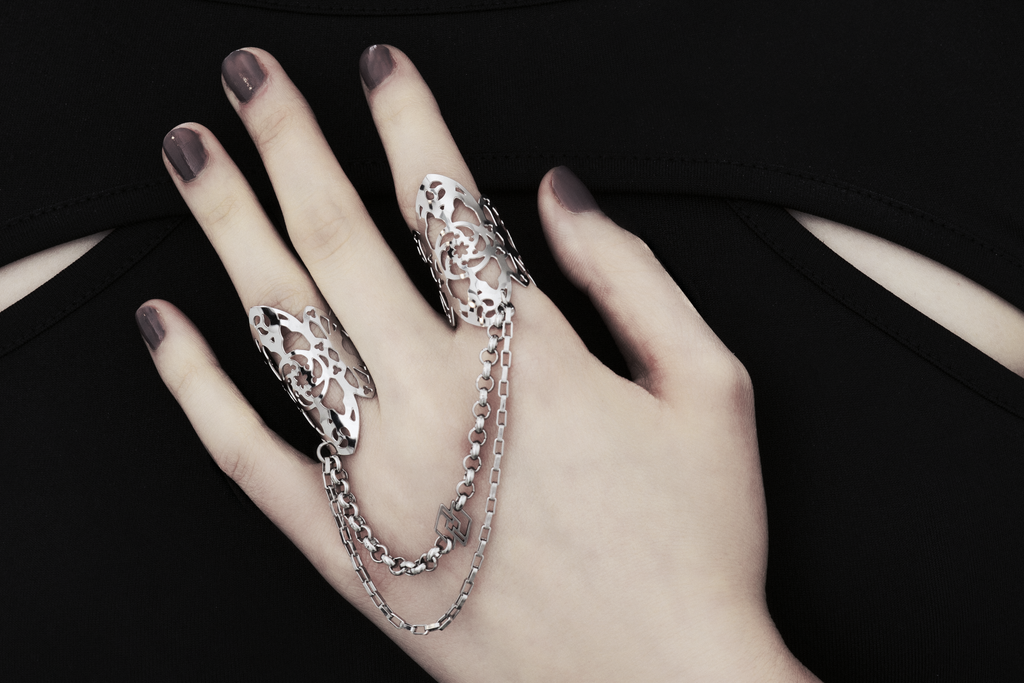 Showcased here is a hand-adorned Myril Jewels double ring, exuding dark sophistication. Crafted with minute gothic details, this piece is perfect for aficionados of the goth and alternative scene. With a design reminiscent of gothic architecture, the slender band proclaims a subtle yet bold elegance. Made in Italy, these rings are a testament to Myril Jewels' distinct and evolving dark avant-garde aesthetic, specifically catered to the refined palate of gothic jewelry admirers.