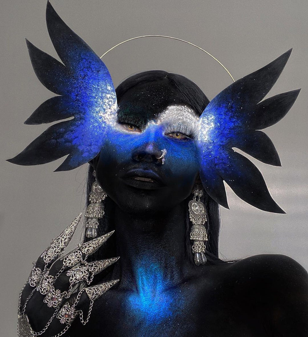 A model captures a celestial look with a makeup theme of deep blues and starry whites, wearing Myril Jewels' full hand silver metal glove with claw rings. The avant-garde jewelry piece complements the mystical, neo-goth aesthetic, perfect for dramatic Halloween events or bold, gothic-chic fashion statements