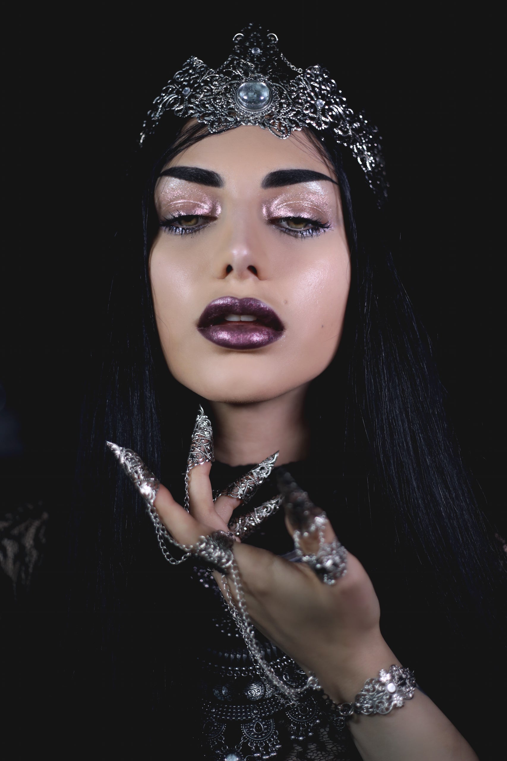Elegant woman with a gothic beauty aesthetic wearing an ornate silver tiara and matching claw rings, connected by fine chains, embodying a vampire goth style with dark makeup and a mysterious allure.