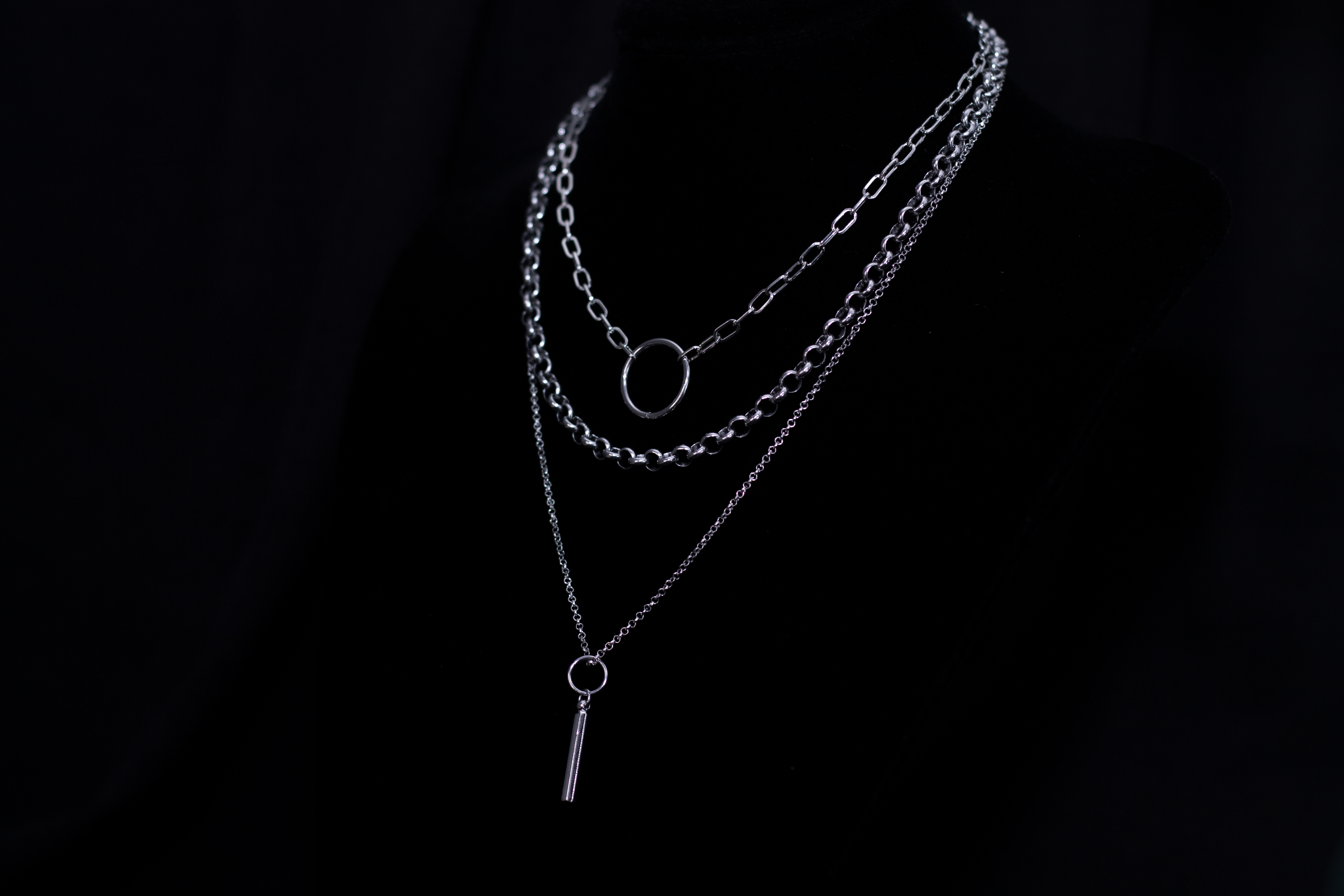 Showcasing a Myril Jewels punk multi-chain necklace with a layered design and a central hoop, this piece is a quintessential neo-goth accessory for an edgy, dark-avantgarde look.