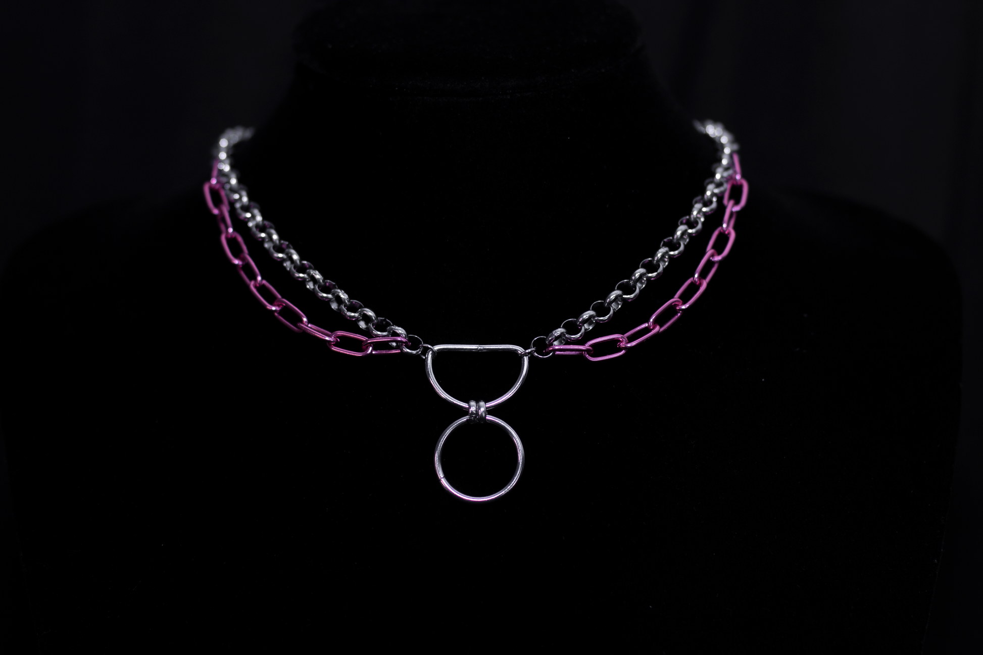 The image features a silver chain necklace with vibrant pink chain details, representing Myril Jewels' blend of neo-gothic charm and avant-garde boldness. This piece is ideal for those who adore punk jewelry or seek a distinctive goth girlfriend gift, adding a pop of color to a minimal goth ensemble or making a statement at rave parties and festivals.