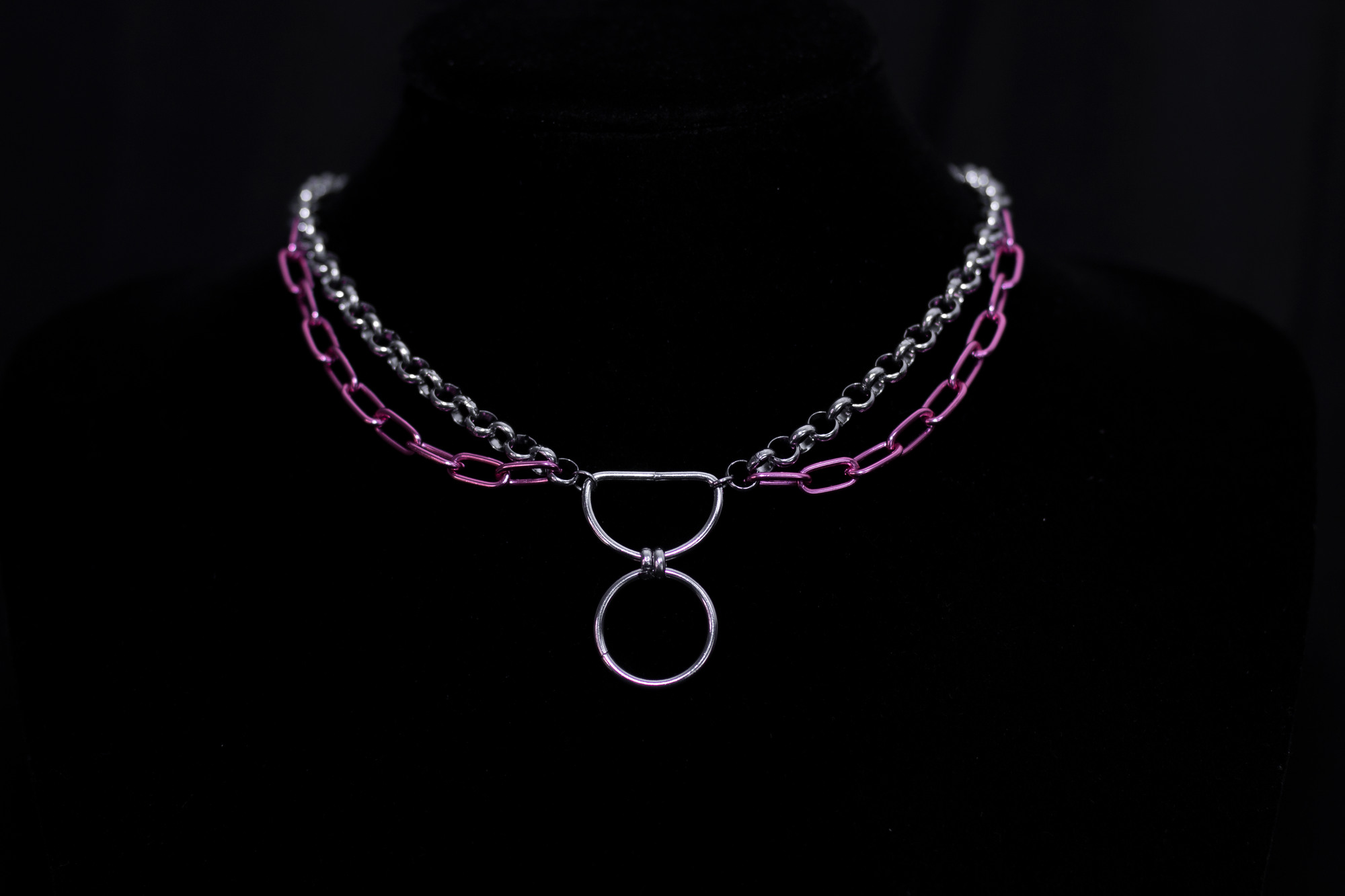 The image features a silver chain necklace with vibrant pink chain details, representing Myril Jewels' blend of neo-gothic charm and avant-garde boldness. This piece is ideal for those who adore punk jewelry or seek a distinctive goth girlfriend gift, adding a pop of color to a minimal goth ensemble or making a statement at rave parties and festivals.