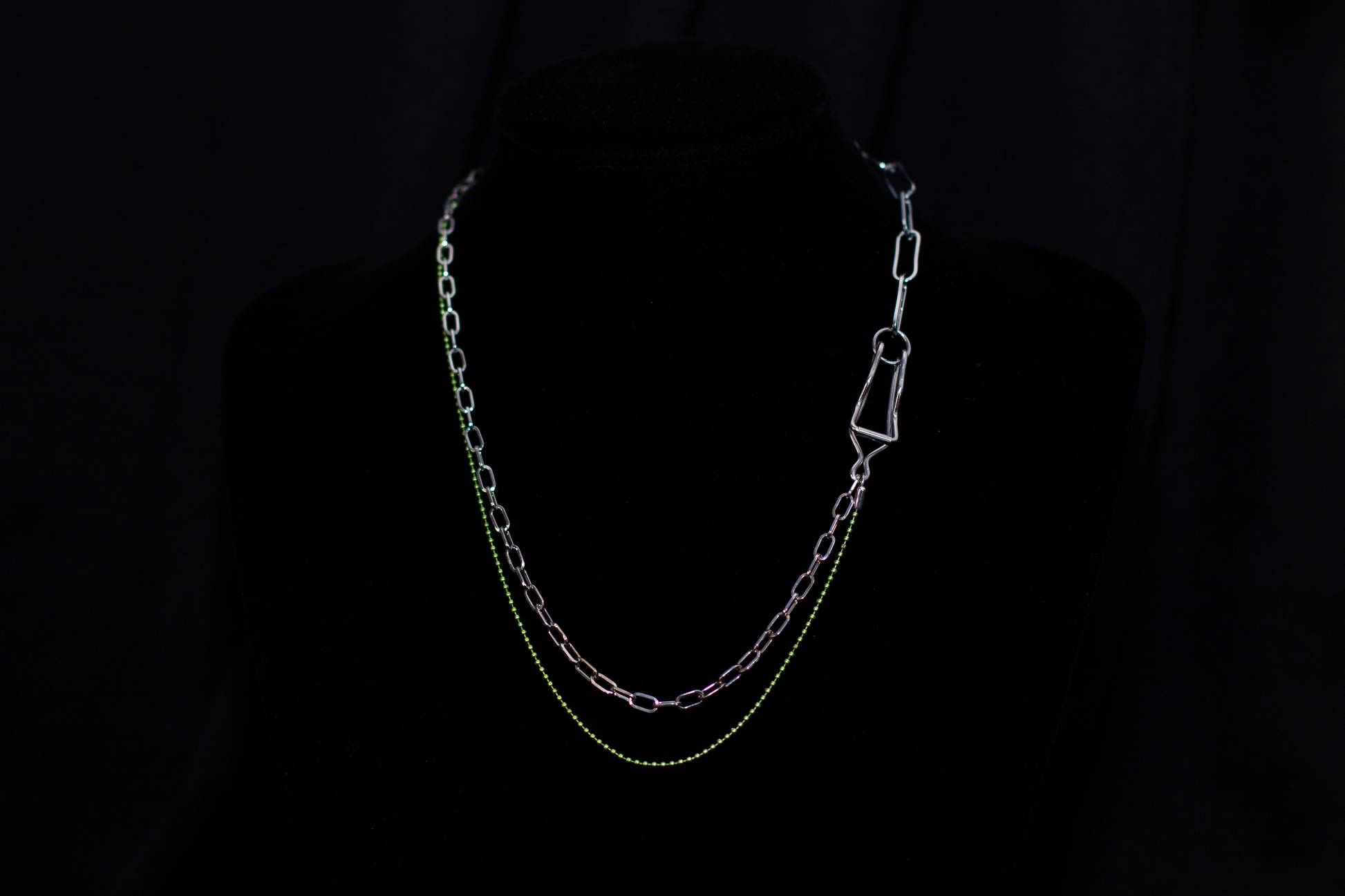  This image showcases a Myril Jewels punk-inspired silver and green chain necklace, artfully displayed on a dark mannequin. The necklace features a mix of classic and oversized links, with a striking green hue that adds a pop of color to the overall dark-avantgarde aesthetic. It's a versatile piece that aligns with neo-gothic trends and caters to gothic, whimsigoth, and witchcore styles, making it a fitting accessory for Halloween, everyday minimal goth fashion, rave parties