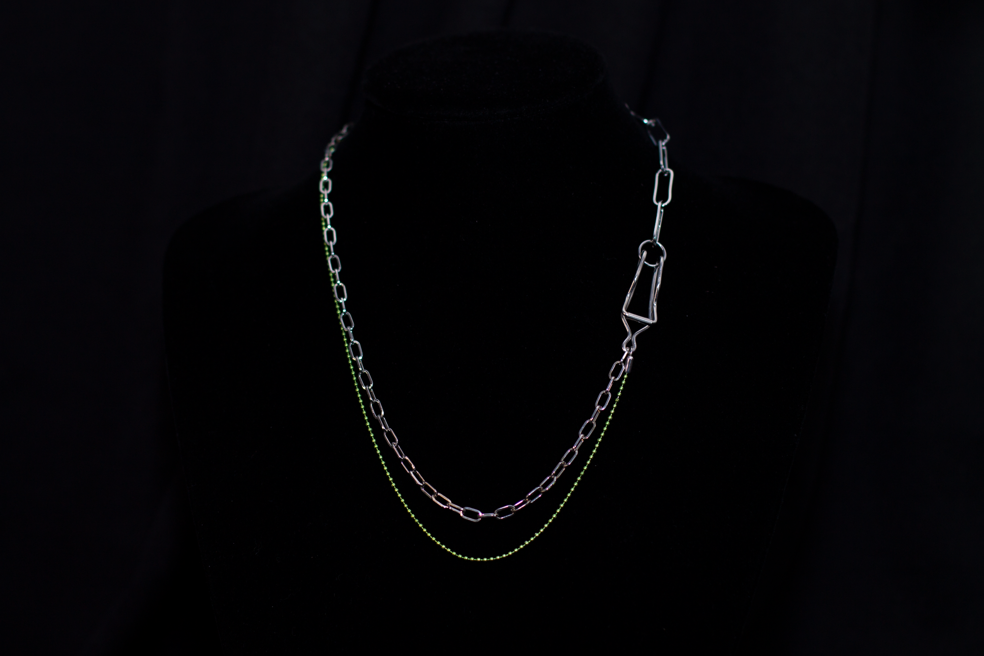  This image showcases a Myril Jewels punk-inspired silver and green chain necklace, artfully displayed on a dark mannequin. The necklace features a mix of classic and oversized links, with a striking green hue that adds a pop of color to the overall dark-avantgarde aesthetic. It's a versatile piece that aligns with neo-gothic trends and caters to gothic, whimsigoth, and witchcore styles, making it a fitting accessory for Halloween, everyday minimal goth fashion, rave parties