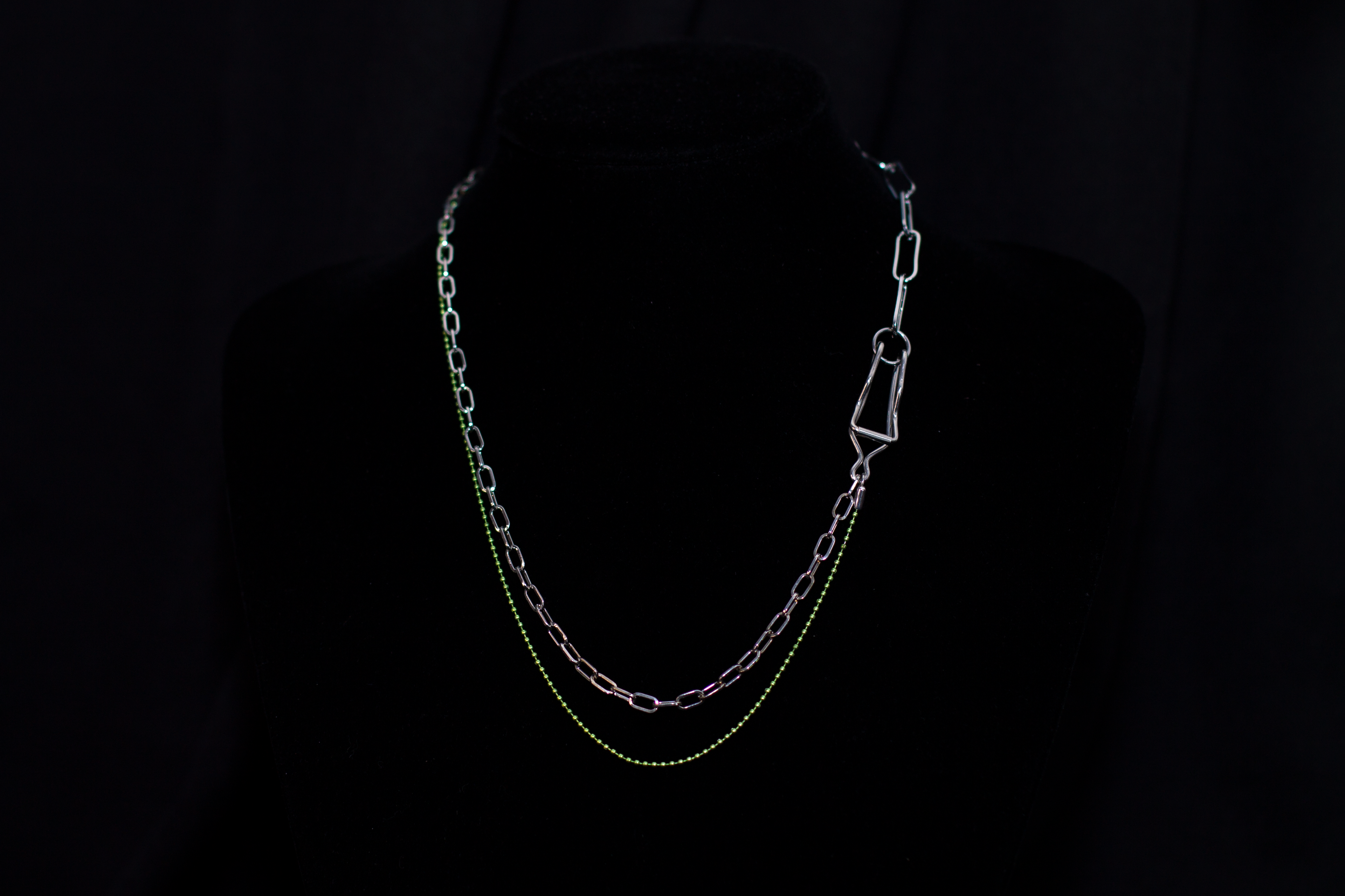  This image showcases a Myril Jewels punk-inspired silver and green chain necklace, artfully displayed on a dark mannequin. The necklace features a mix of classic and oversized links, with a striking green hue that adds a pop of color to the overall dark-avantgarde aesthetic. It's a versatile piece that aligns with neo-gothic trends and caters to gothic, whimsigoth, and witchcore styles, making it a fitting accessory for Halloween, everyday minimal goth fashion, rave parties