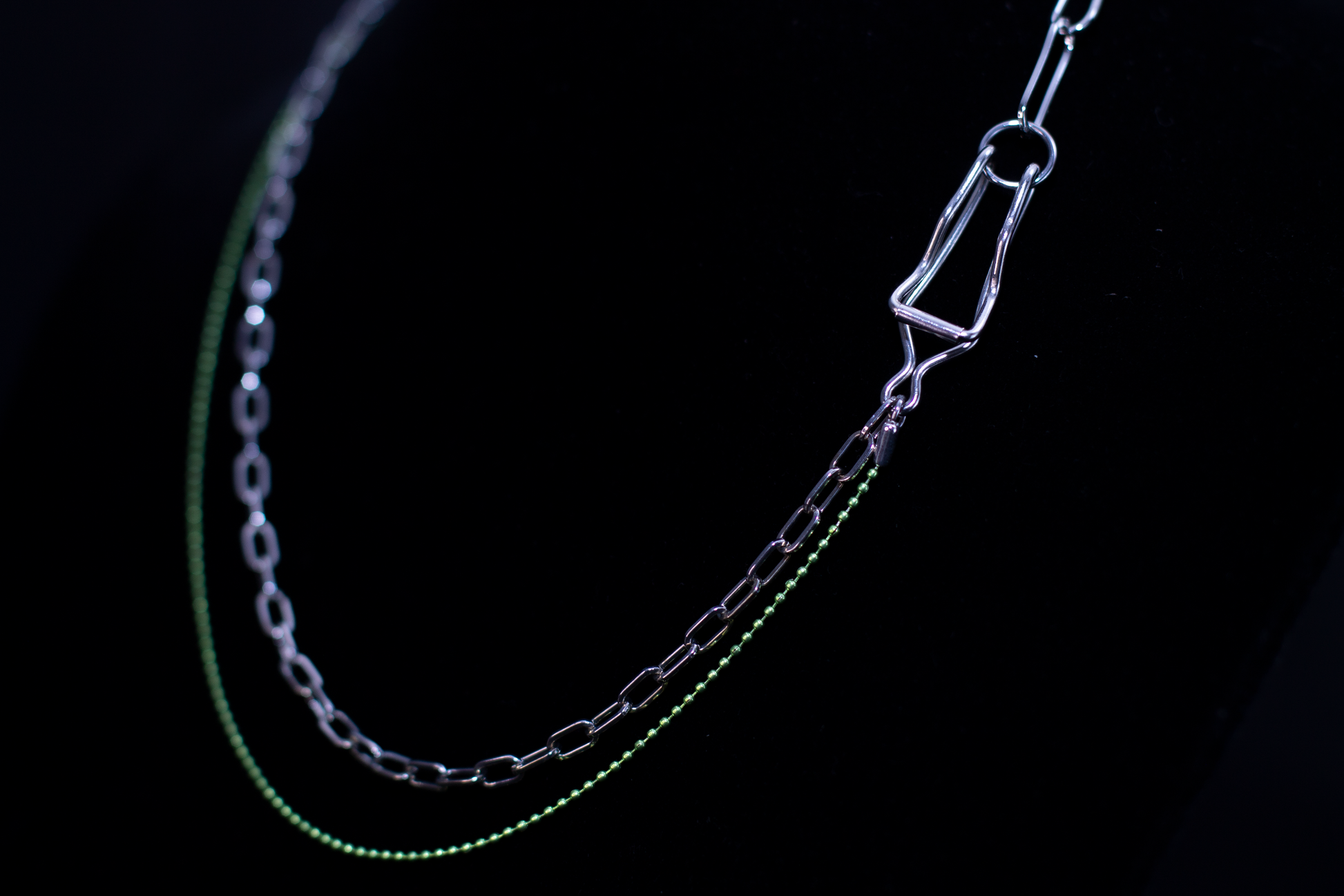 This image showcases a Myril Jewels punk silver and green chain necklace, displayed on a dark backdrop. The necklace features a contrast of sleek silver links with vibrant green accents, encapsulating the neo-goth aesthetic. It's a striking piece for those drawn to dark-avantgarde fashion, perfect for Halloween, and versatile for everyday wear, from minimal goth to the more elaborate witchcore and whimsigoth styles, as well as being suitable for rave parties and festival adornment.