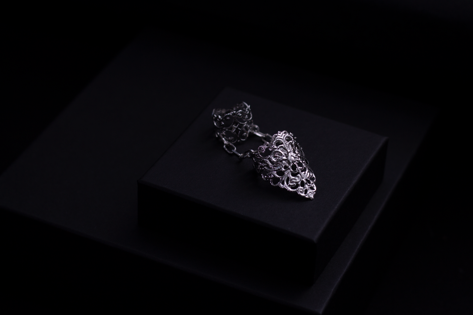 A Myril Jewels gothic double ring is featured, reflecting a neo-goth aesthetic with intricate detailing, perfect for a bold fashion statement. It is an ideal piece for those who favor dark, avant-garde accessories, suitable for Halloween, everyday wear, and rave parties. This piece can serve as a distinctive goth girlfriend gift or a creative addition to a drag queen's jewel collection.