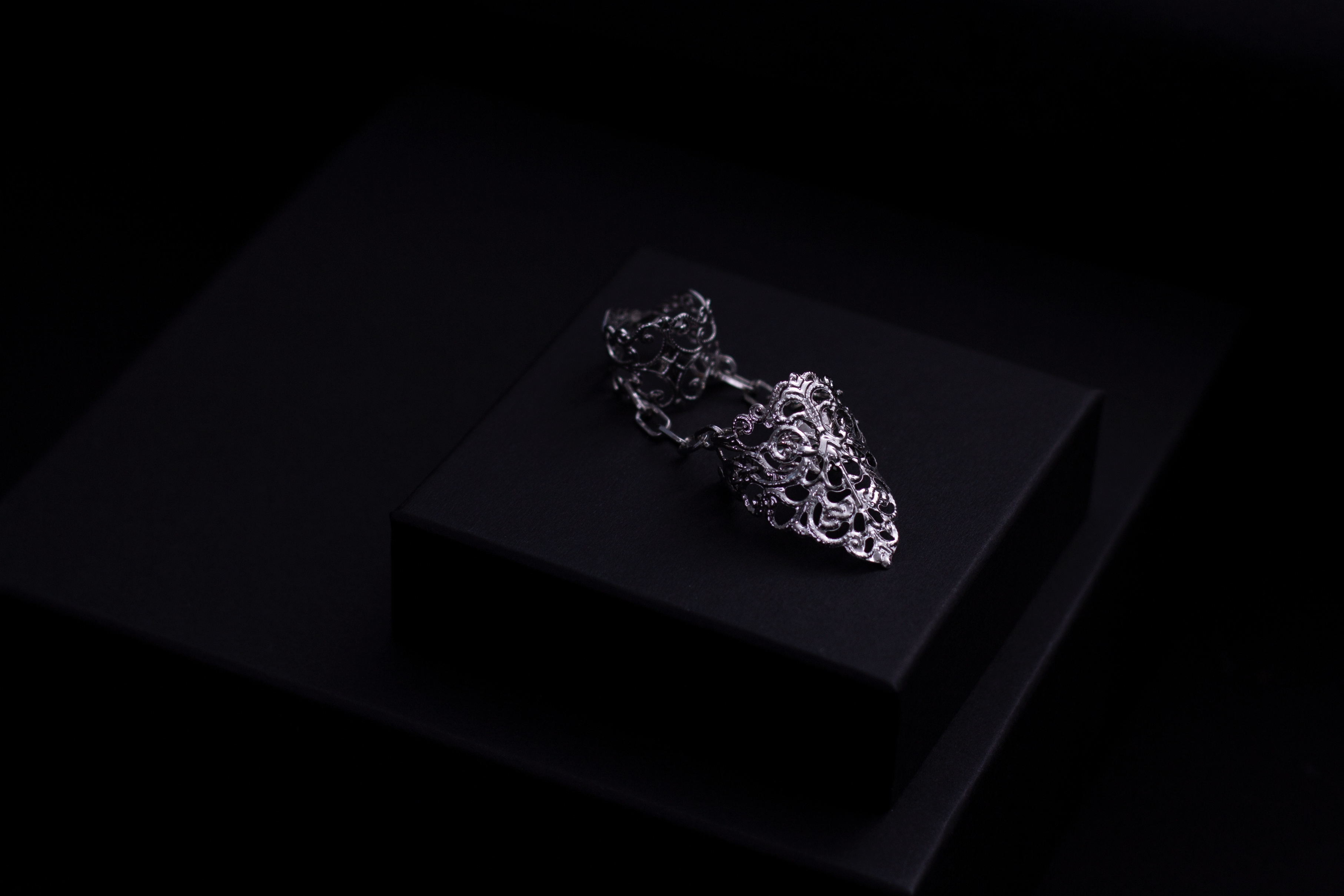 A Myril Jewels gothic double ring is featured, reflecting a neo-goth aesthetic with intricate detailing, perfect for a bold fashion statement. It is an ideal piece for those who favor dark, avant-garde accessories, suitable for Halloween, everyday wear, and rave parties. This piece can serve as a distinctive goth girlfriend gift or a creative addition to a drag queen's jewel collection.
