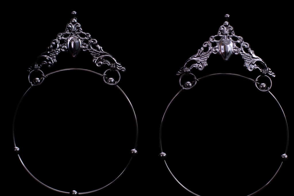 Showcasing Myril Jewels’ bold gothic hoop earrings, these pieces flaunt wide loops with ornate, gothic-inspired filigree and a central teardrop gemstone, radiating dark elegance. Ideal for the gothic-chic, these earrings are a statement accessory for Halloween, festivals, or as a distinctive gift for the goth-loving friend