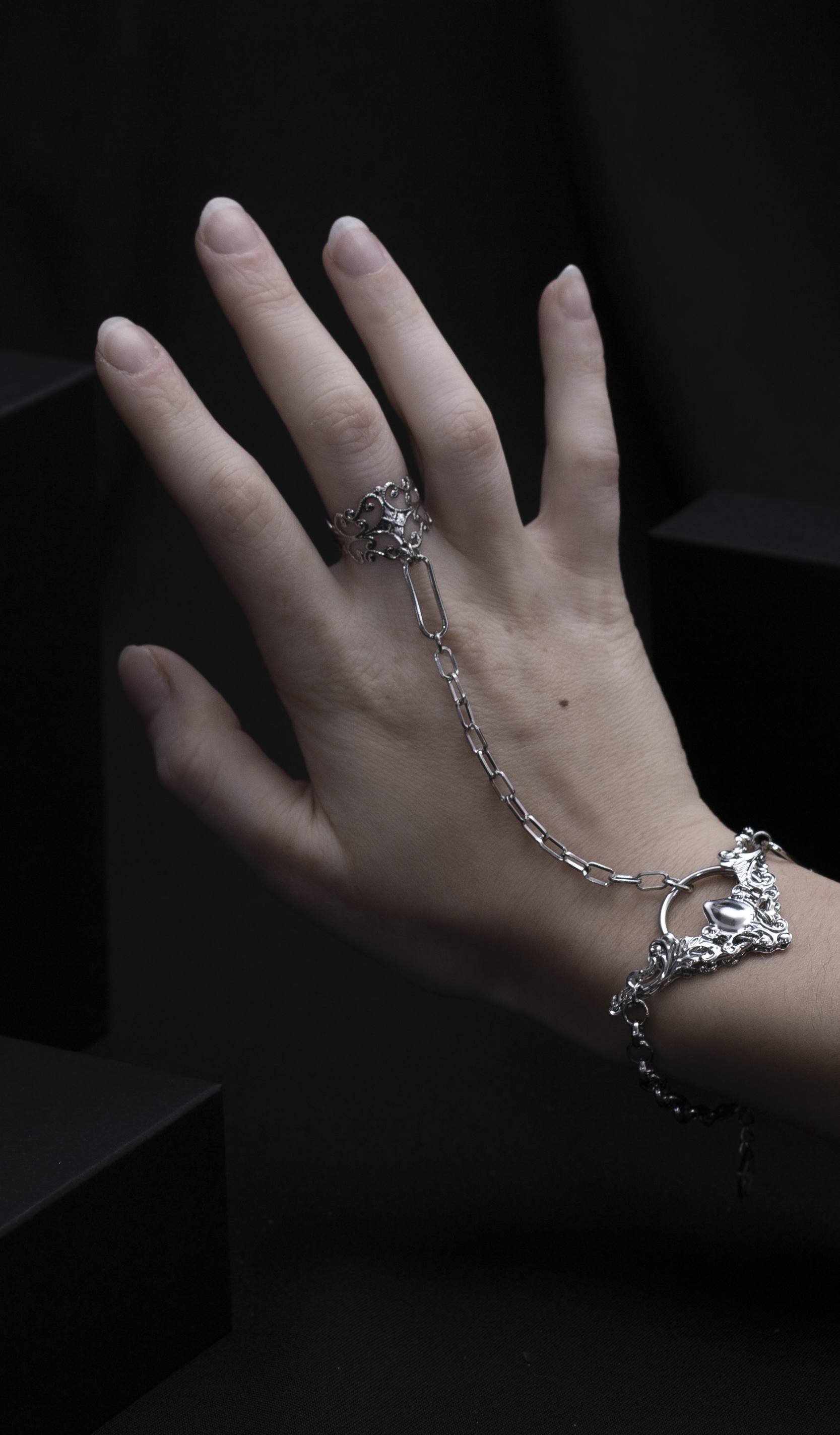 Elegant Myril Jewels hand chain bracelet ring, intricately designed, casting a neo-gothic statement for those who celebrate dark-avantgarde fashion, showcased against a shadowed background