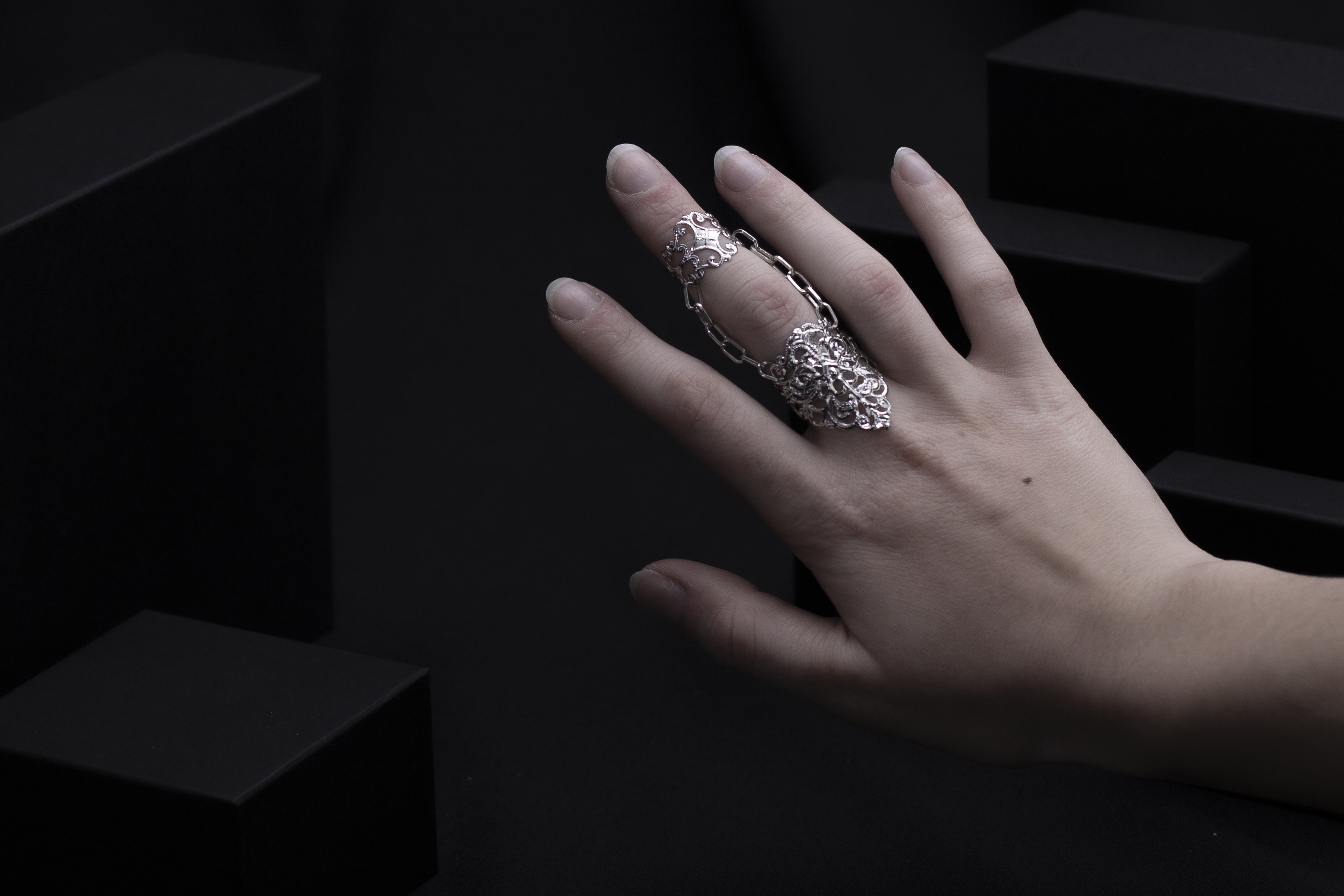 An artistic representation of Myril Jewels' craftsmanship, this gothic double ring spans across two fingers. The ring boasts neo-gothic intricacy, ideal for a dark, avant-garde fashion statement. It's a versatile accessory suited for minimal goth daily wear or as a standout piece at festivals and rave parties, making it a thoughtful gift for the goth-loving friend in your life.