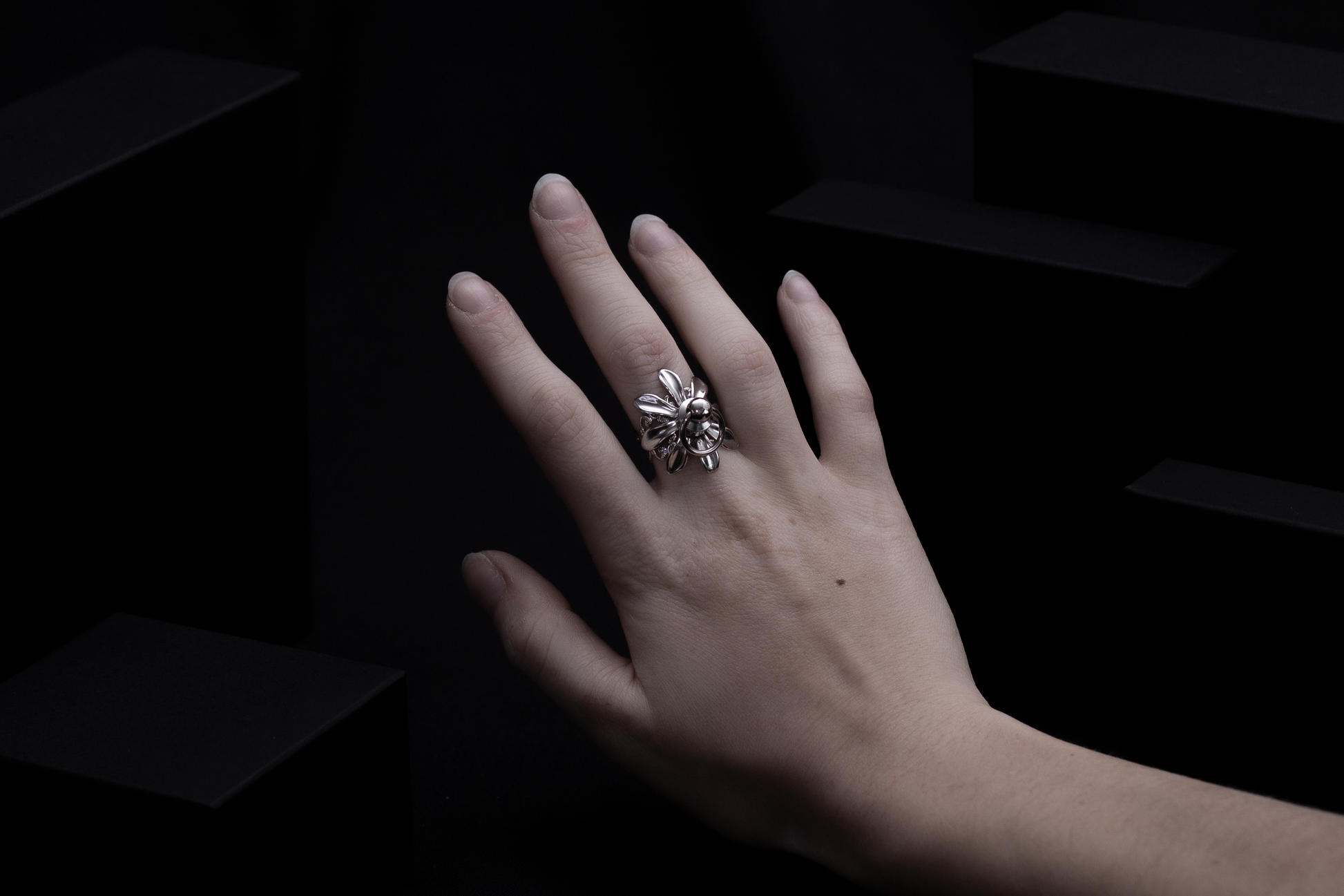 A solitary hand displays a Myril Jewels flower ring, a masterpiece of dark-avantgarde jewelry. The ring's silver sheen and intricate floral design embody the luxurious, gothic aesthetic, a signature of Myril Jewels, catering to those with a penchant for bold, alternative fashion.