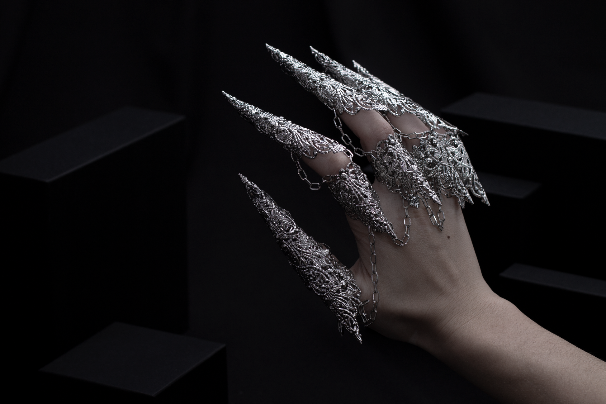 A hand is strikingly adorned with a set of Myril Jewels' dragon-like long claw rings, casting a neo-gothic spell. This bold jewelry, embodying the essence of dark avant-garde, is a dream for gothic style enthusiasts, making it an ideal choice for Halloween or as a unique gift.