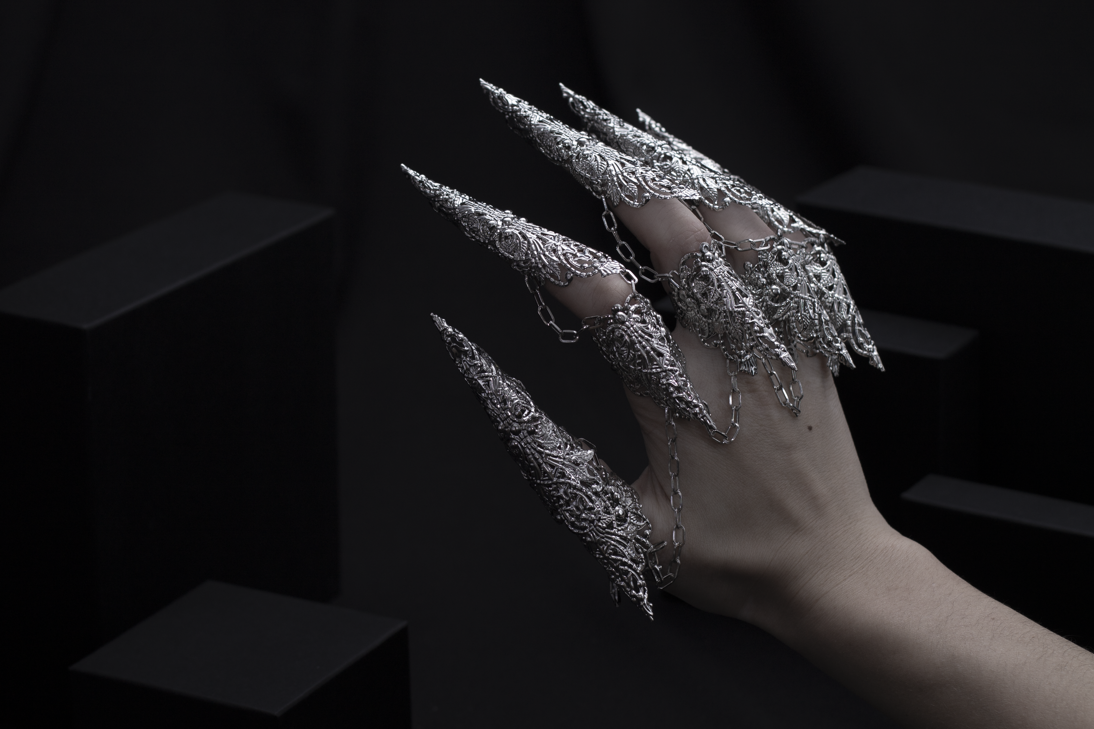 A hand is strikingly adorned with a set of Myril Jewels' dragon-like long claw rings, casting a neo-gothic spell. This bold jewelry, embodying the essence of dark avant-garde, is a dream for gothic style enthusiasts, making it an ideal choice for Halloween or as a unique gift.