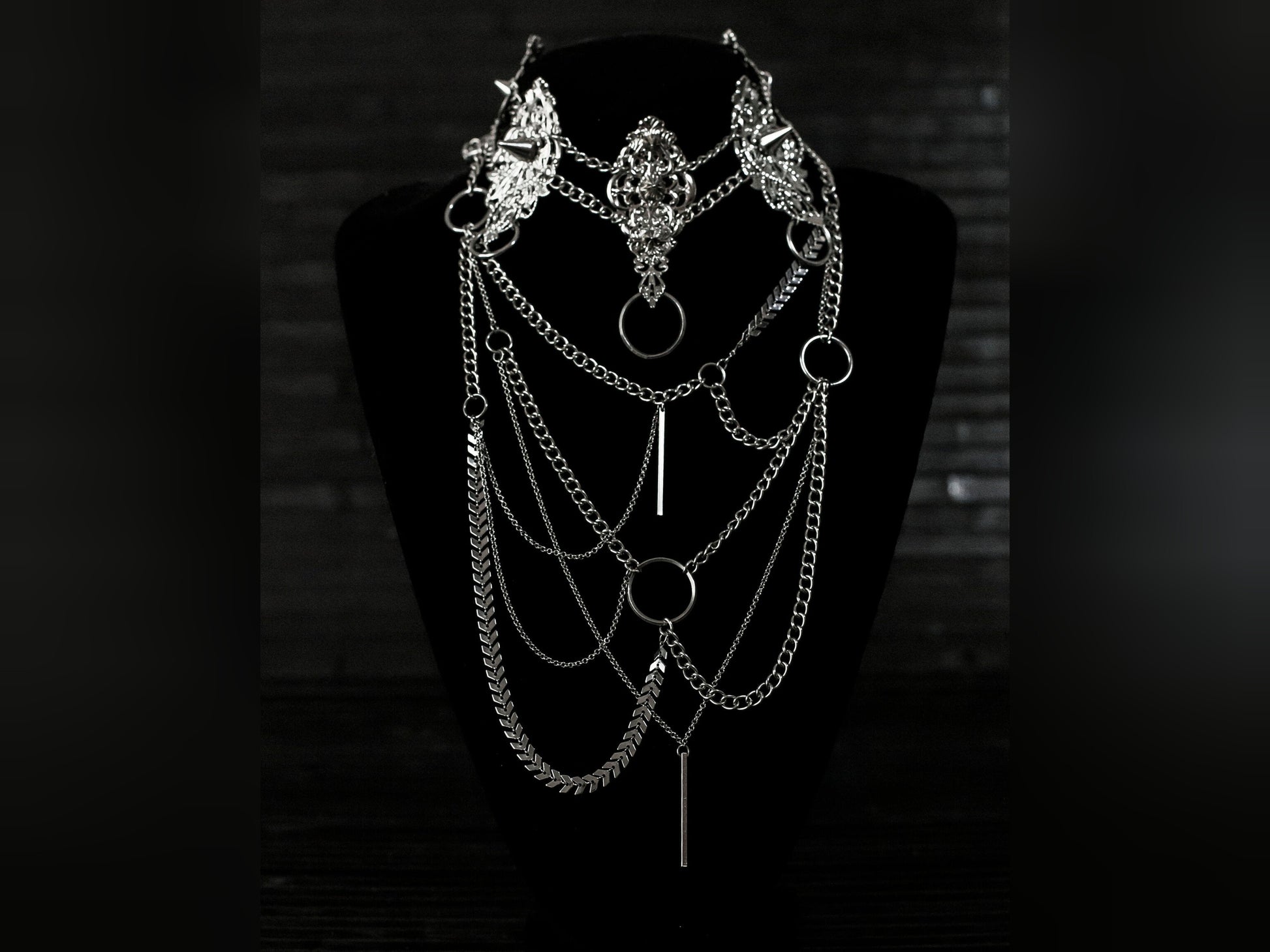 Myril Jewels presents an exquisite punk studded metal choker paired with a multi-layer long chain necklace, embodying the dark avant-garde spirit. This Italian handcrafted ensemble is a testament to the fusion of Neo Gothic flair and Gothic-chic, perfect for Halloween, everyday wear, or any whimsigoth and witchcore inspired look. The layered chains add depth to the minimal goth aesthetic, making it a versatile statement piece for alternative style connoisseurs