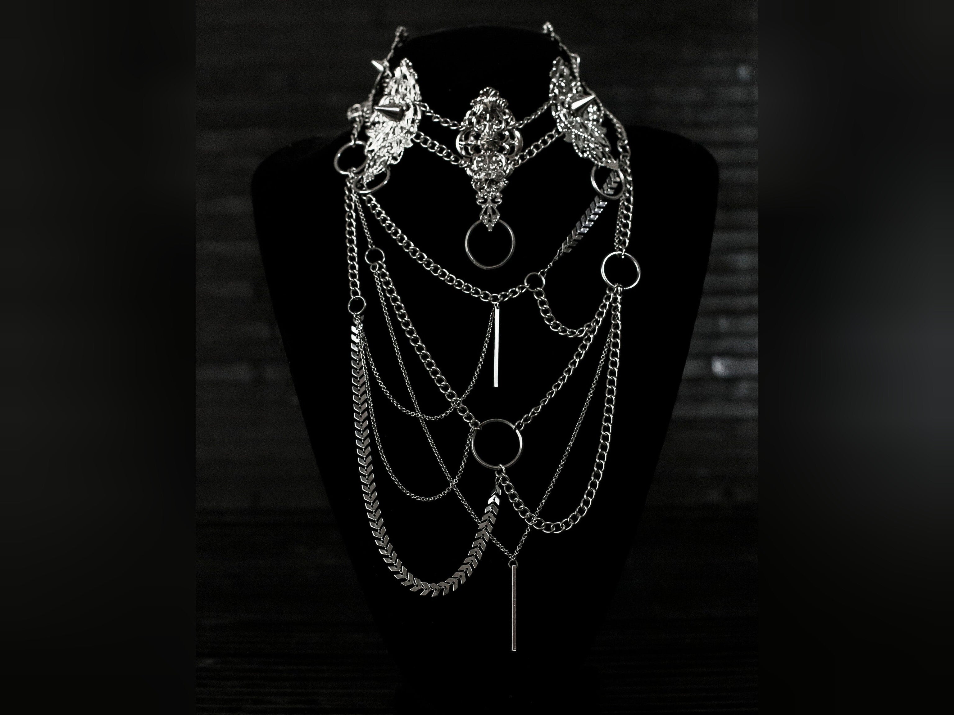 Myril Jewels presents an exquisite punk studded metal choker paired with a multi-layer long chain necklace, embodying the dark avant-garde spirit. This Italian handcrafted ensemble is a testament to the fusion of Neo Gothic flair and Gothic-chic, perfect for Halloween, everyday wear, or any whimsigoth and witchcore inspired look. The layered chains add depth to the minimal goth aesthetic, making it a versatile statement piece for alternative style connoisseurs