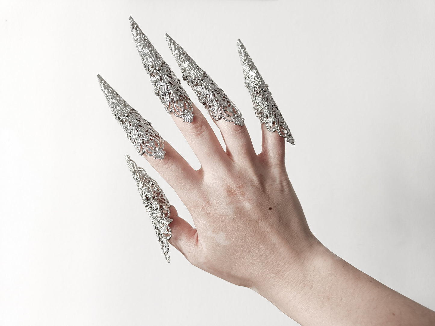 A hand adorned with a full set of Myril Jewels' extra long nail claw rings, showcasing a stunning neo-gothic design. These claws are a must-have for Halloween, adding a dark and bold edge to gothic-chic and witchcore styles, and are perfect for everyday wear or as a statement piece at a rave party or festival.