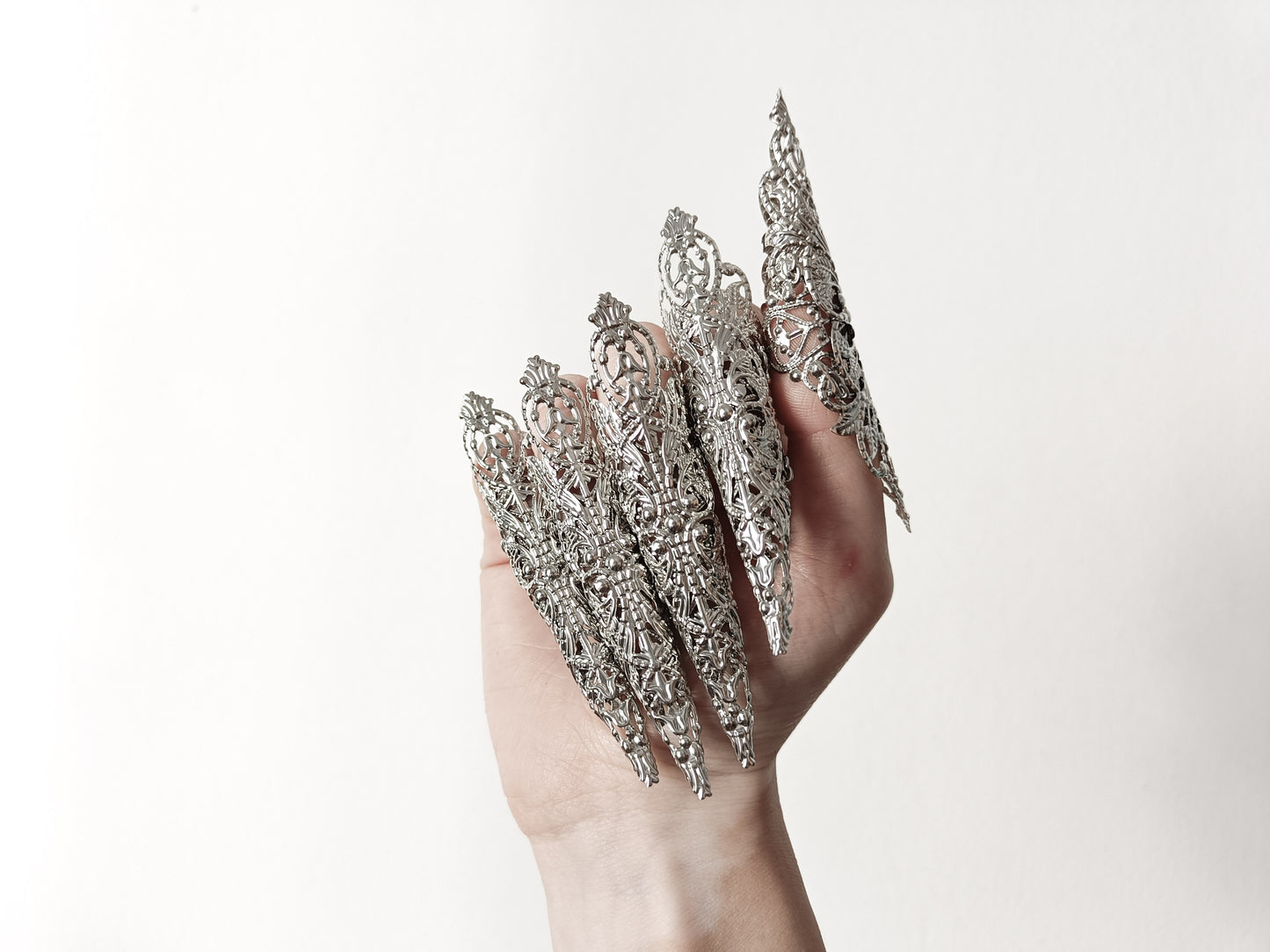 A hand adorned with a full set of Myril Jewels' extra long nail claw rings, showcasing a stunning neo-gothic design. These claws are a must-have for Halloween, adding a dark and bold edge to gothic-chic and witchcore styles, and are perfect for everyday wear or as a statement piece at a rave party or festival.