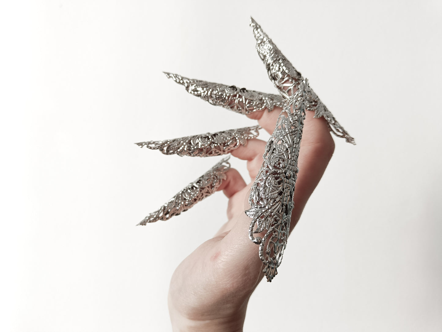 A hand adorned with a full set of Myril Jewels' extra long nail claw rings, showcasing a stunning neo-gothic design. These claws are a must-have for Halloween, adding a dark and bold edge to gothic-chic and witchcore styles, and are perfect for everyday wear or as a statement piece at a rave party or festival.