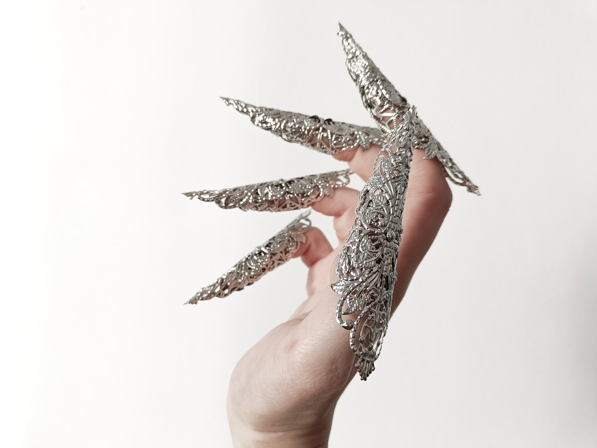 A hand adorned with a full set of Myril Jewels' extra long nail claw rings, showcasing a stunning neo-gothic design. These claws are a must-have for Halloween, adding a dark and bold edge to gothic-chic and witchcore styles, and are perfect for everyday wear or as a statement piece at a rave party or festival.