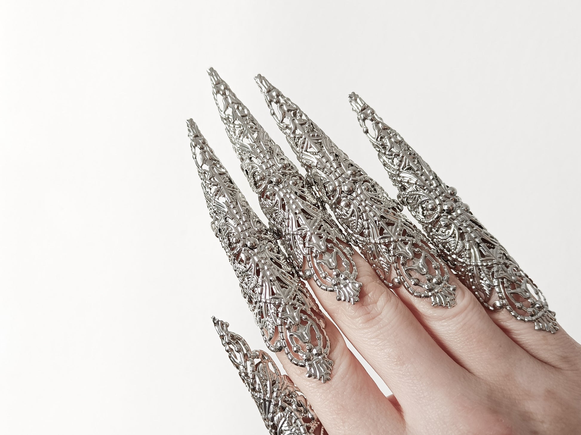 A hand adorned with a full set of Myril Jewels' extra long nail claw rings, showcasing a stunning neo-gothic design. These claws are a must-have for Halloween, adding a dark and bold edge to gothic-chic and witchcore styles, and are perfect for everyday wear or as a statement piece at a rave party or festival.