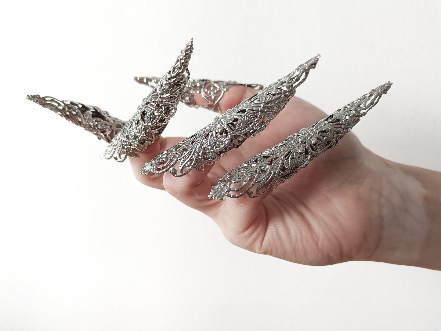 A hand adorned with a full set of Myril Jewels' extra long nail claw rings, showcasing a stunning neo-gothic design. These claws are a must-have for Halloween, adding a dark and bold edge to gothic-chic and witchcore styles, and are perfect for everyday wear or as a statement piece at a rave party or festival.