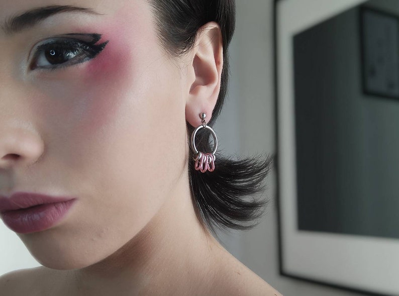 Model showcases Myril Jewels' small silver hoop earrings with vibrant pink detail, exuding neo-goth elegance. Ideal for adding a subtle yet bold statement to gothic-chic or everyday attire, perfect for festival adornment or as a unique goth girlfriend gift