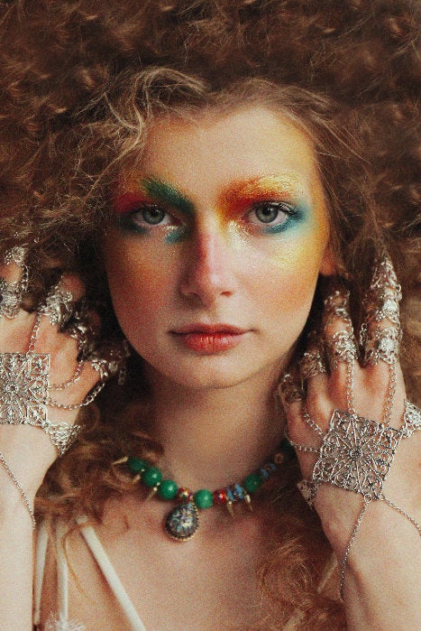 A model in a Vogue editorial exudes a bohemian neo-goth vibe, wearing a Myril Jewels full hand silver metal glove with ornate claw rings. Her rainbow-hued eye makeup complements the intricate gothic-chic jewelry, perfect for anyone who cherishes bold, dark avant-garde fashion.