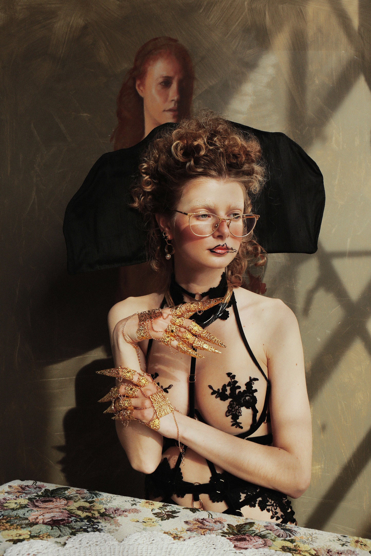 In a vogue editorial, a model strikes a pose with Myril Jewels' luxurious full hand gold metal glove, adorned with claw rings. The opulent neo-goth piece complements her avant-garde look, perfect for gothic-chic aficionados and a bold statement at any upscale event or festival.