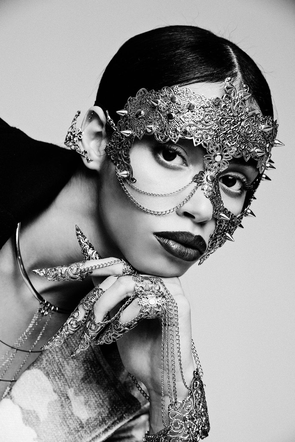 A dramatic monochrome image captures a fashion model adorned with Myril Jewels' exquisite metal glove with finger claw rings. The glove's elaborate craftsmanship exemplifies neo-goth jewelry, perfect for Halloween, punk, or gothic-chic style aficionados seeking unique, bold accessories.