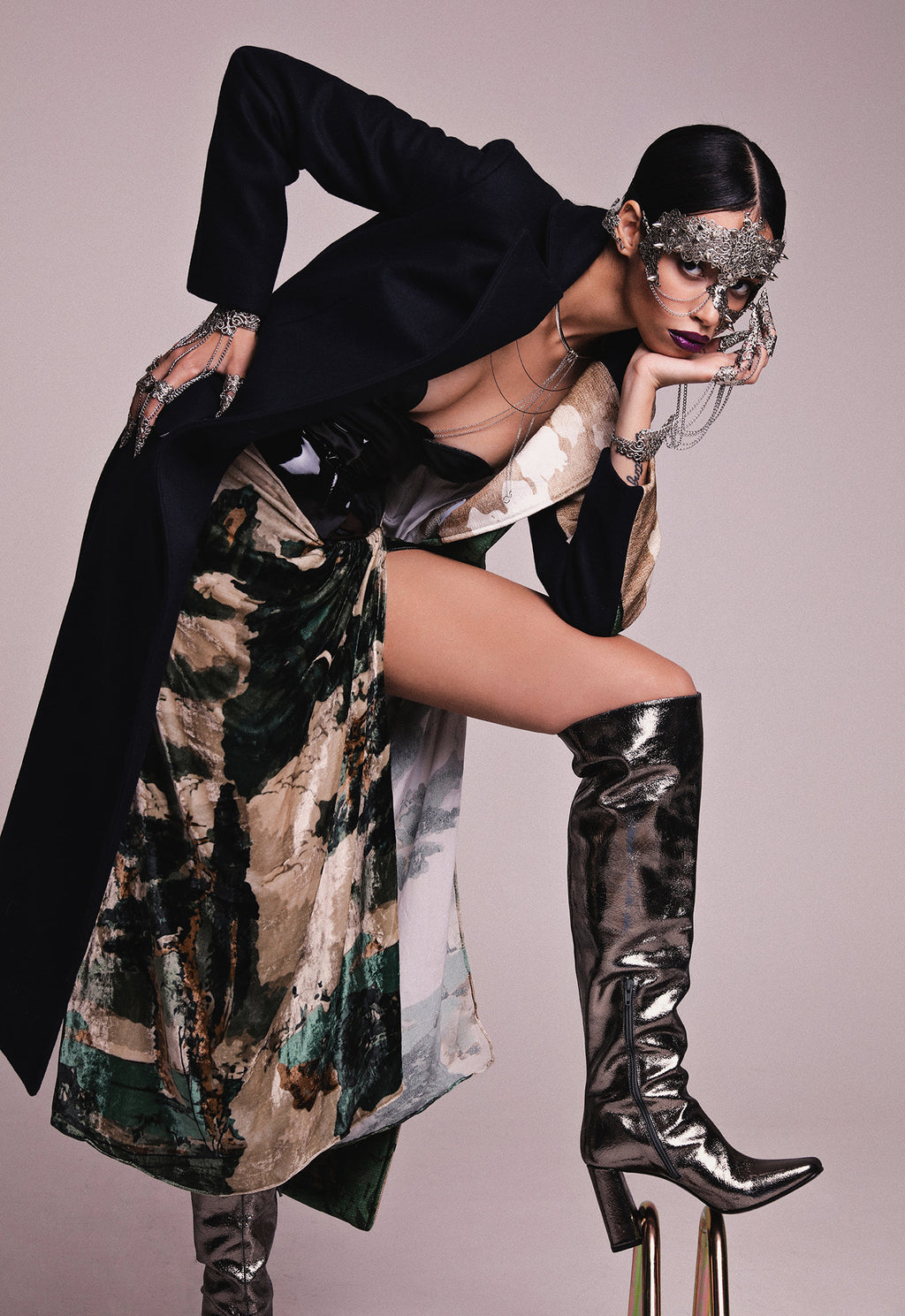 In a high-fashion pose, a model sports a daring look with a Myril Jewels metal glove featuring elegant finger claw rings. The avant-garde accessory complements her stylized mask and dynamic ensemble, embodying neo-goth luxury for the trendsetting gothic and alternative fashion lover.