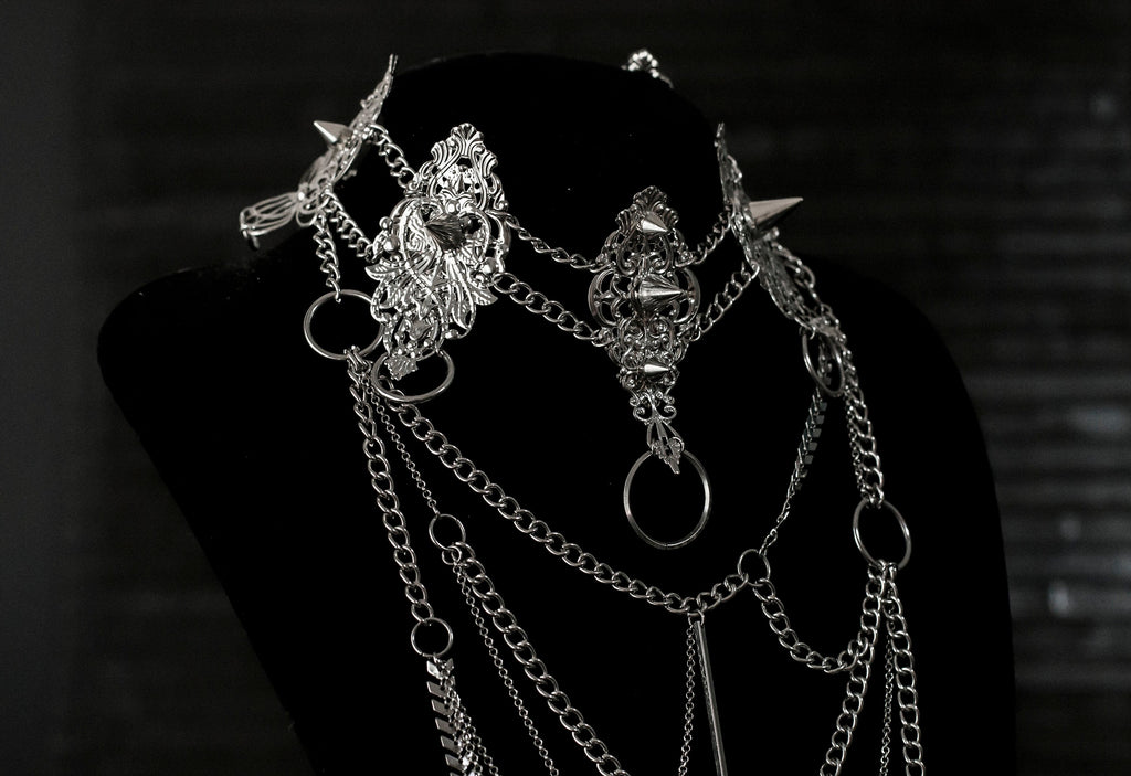 Myril Jewels presents an exquisite punk studded metal choker paired with a multi-layer long chain necklace, embodying the dark avant-garde spirit. This Italian handcrafted ensemble is a testament to the fusion of Neo Gothic flair and Gothic-chic, perfect for Halloween, everyday wear, or any whimsigoth and witchcore inspired look. The layered chains add depth to the minimal goth aesthetic, making it a versatile statement piece for alternative style connoisseurs