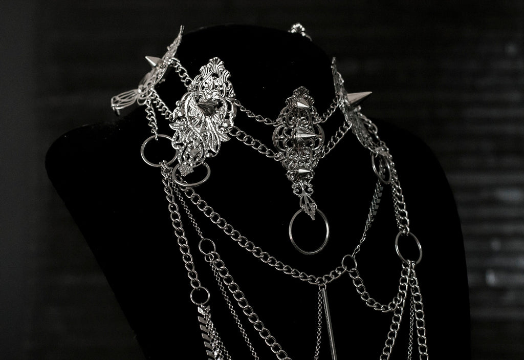 Myril Jewels presents an exquisite punk studded metal choker paired with a multi-layer long chain necklace, embodying the dark avant-garde spirit. This Italian handcrafted ensemble is a testament to the fusion of Neo Gothic flair and Gothic-chic, perfect for Halloween, everyday wear, or any whimsigoth and witchcore inspired look. The layered chains add depth to the minimal goth aesthetic, making it a versatile statement piece for alternative style connoisseurs