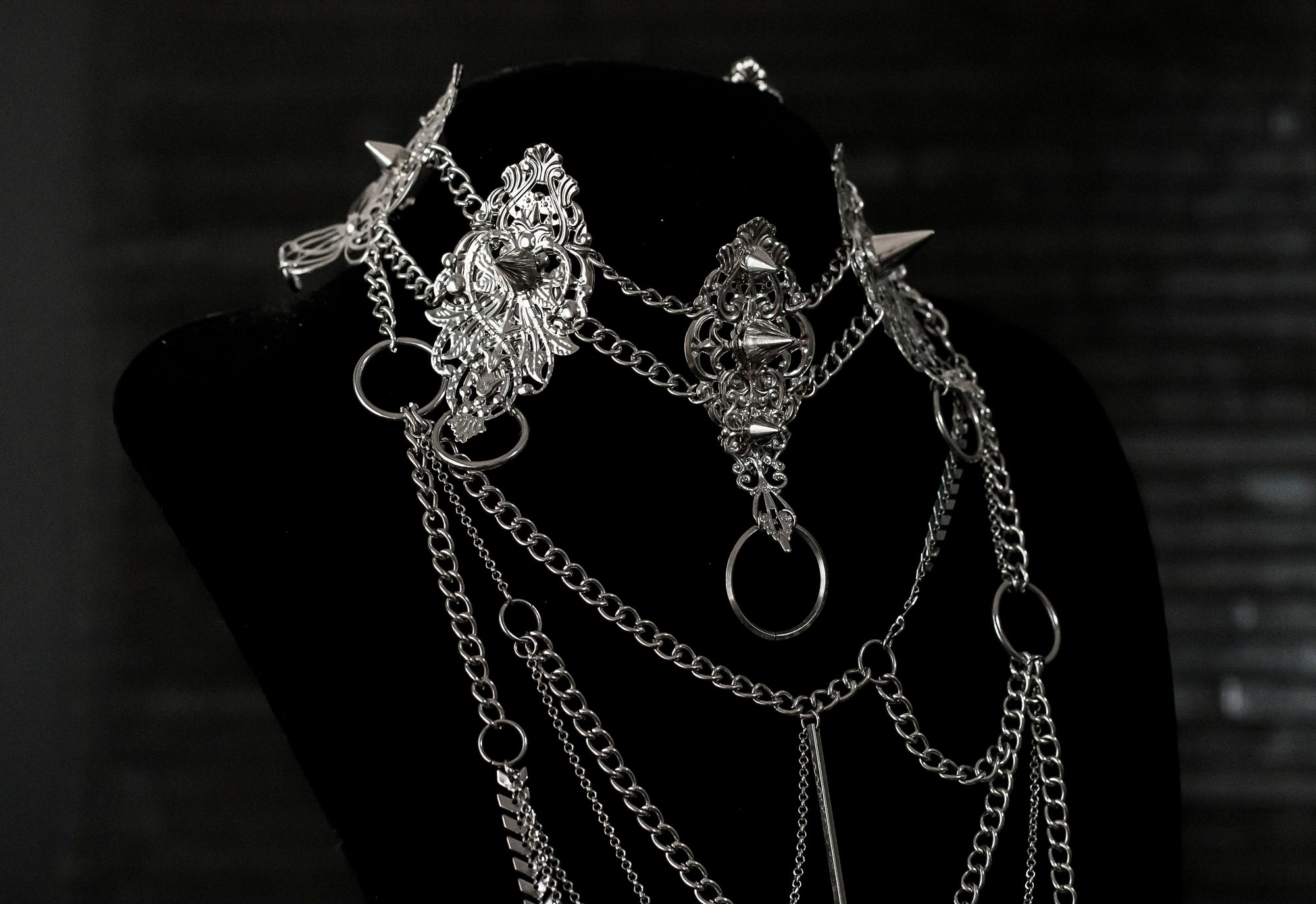 Myril Jewels presents an exquisite punk studded metal choker paired with a multi-layer long chain necklace, embodying the dark avant-garde spirit. This Italian handcrafted ensemble is a testament to the fusion of Neo Gothic flair and Gothic-chic, perfect for Halloween, everyday wear, or any whimsigoth and witchcore inspired look. The layered chains add depth to the minimal goth aesthetic, making it a versatile statement piece for alternative style connoisseurs